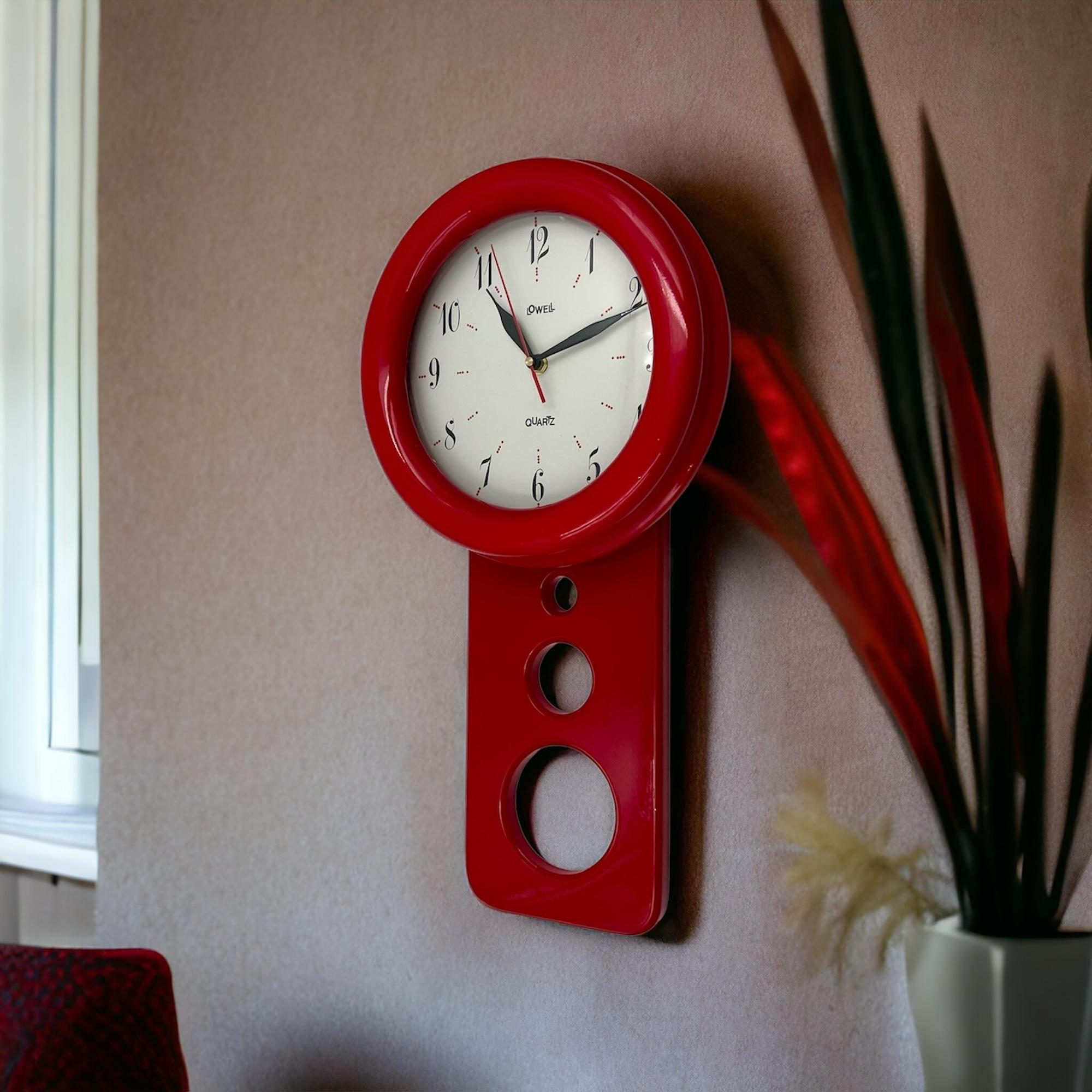 Add a touch of retro elegance to your space with this stunning 80s wall clock by the renowned Italian maker Lowell. Featuring a distinctive pendulum-like shape, this large wall clock is crafted from lacquered red wood, making it a bold and