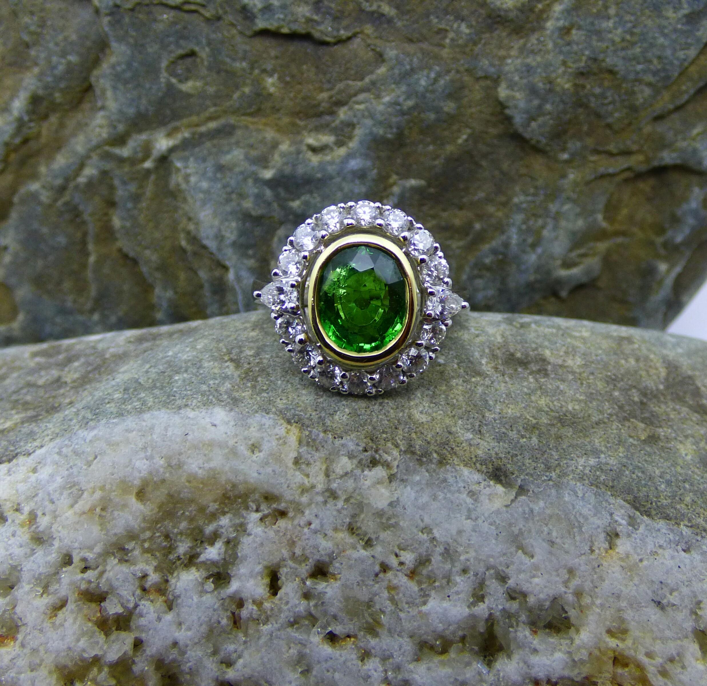 Ein sehr heller und farbenfroher ovaler 8,12-karätiger Tsavorit-Granat macht diesen Ring zum Hingucker. Der 9X7mm große Granat ist umgeben von 14 runden Diamanten mit einem Gesamtgewicht von 0,92ct und einem birnenförmigen Diamanten auf jeder Seite