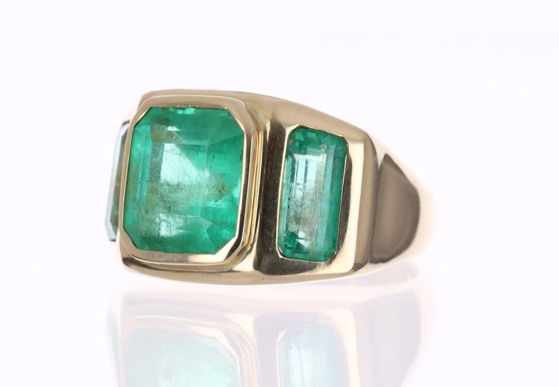 A Colombian emerald three-stone gypsy ring. Dexterously handcrafted in gleaming 14K yellow gold, this ring features earth-mined Colombian emeralds, Emerald & Asscher cuts from the famous Muzo mines. Set in a secure bezel setting for a lifetime of