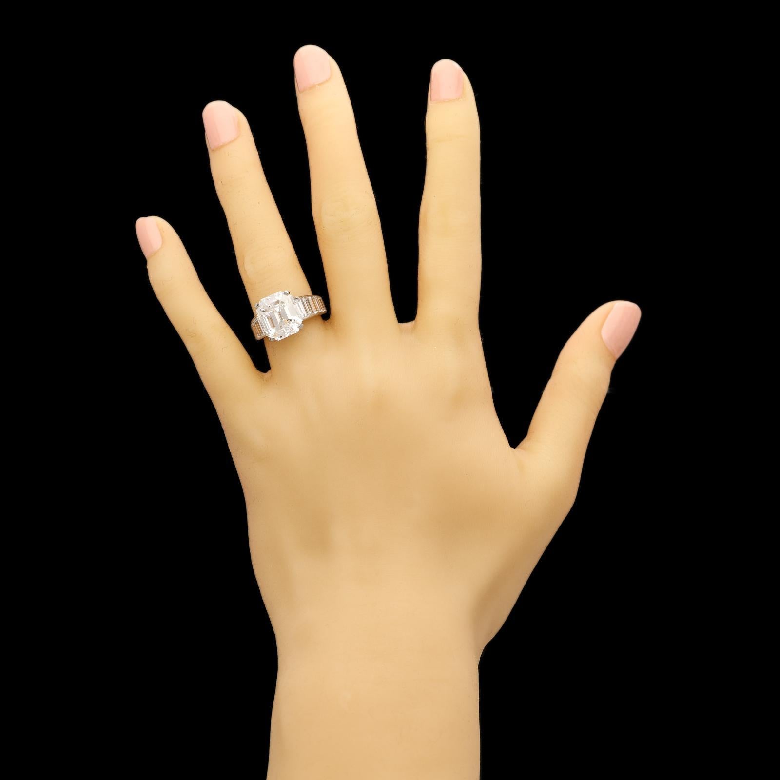 A stunning diamond ring by Cartier c.1980s, set to the centre with a beautiful vinatage emerald-cut diamond with deeply angled corners in a platinum claw setting, the simple open gallery set to the base each side with a single baguette diamond, the