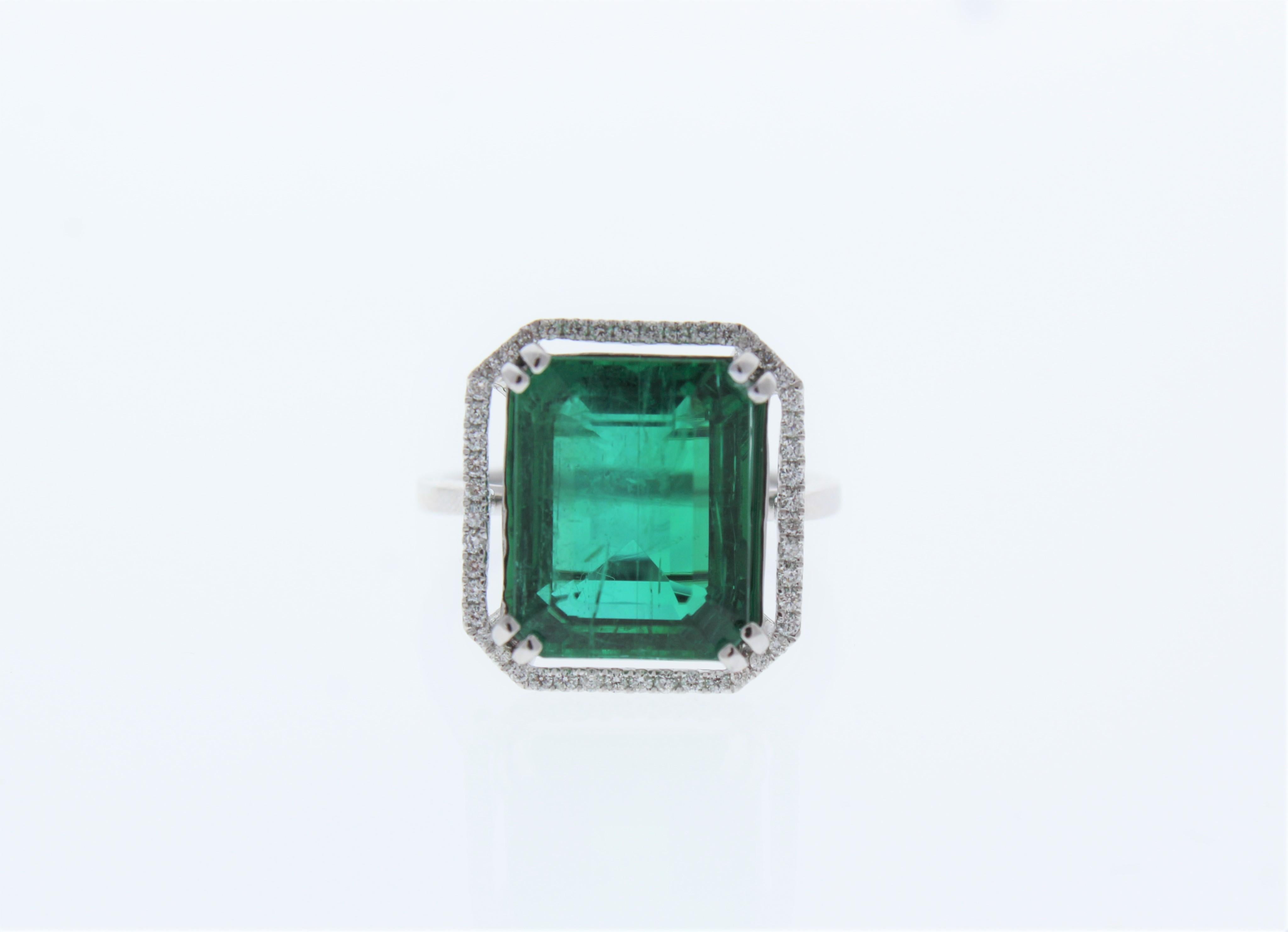 Es handelt sich um einen grasgrünen Smaragd von 8,24 Karat im Smaragdschliff. Funkelnde, runde Diamanten im Brillantschliff umrahmen den zentralen Edelstein und bilden einen Halo von insgesamt 0,25 Karat. Ein schmales, diamantenes Band mit geteiltem
