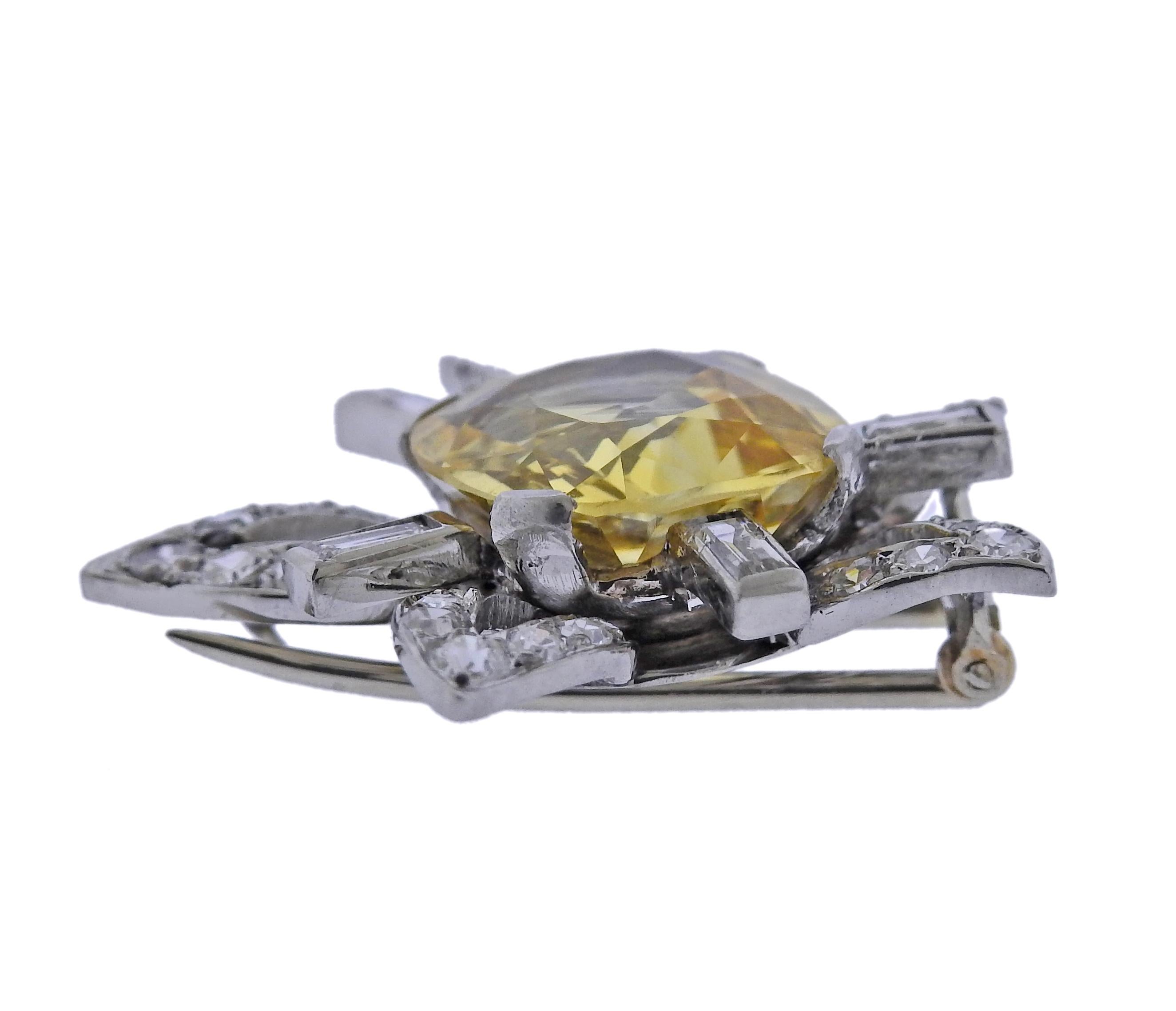 Platinum brooch, set with center approx. 8.24ct yellow sapphire (measures 12.7 x 11.89 x 6.2mm), surrounded with approx. 0.74ctw in diamonds. Brooch measures 28mm x 27mm. Tested plat. Weight - 10.3 grams.