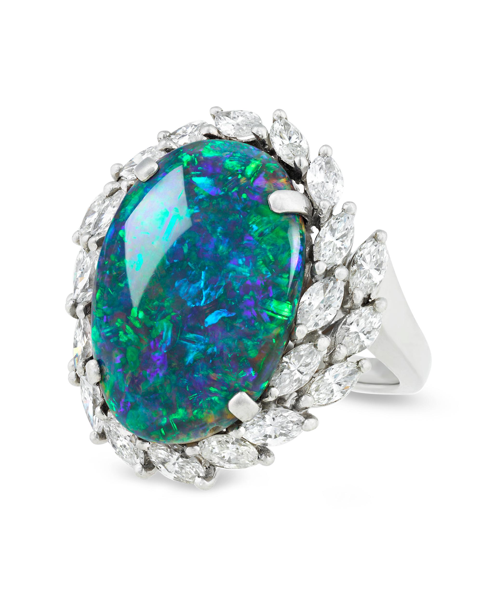 Crowned by a laurel motif of white diamonds, this ravishing black opal is set apart by its dynamic beauty and exceptional color. Weighing 8.28 carats, this stunning gem exhibits fiery reds and oranges harmonizing with cool purples, blues and greens,