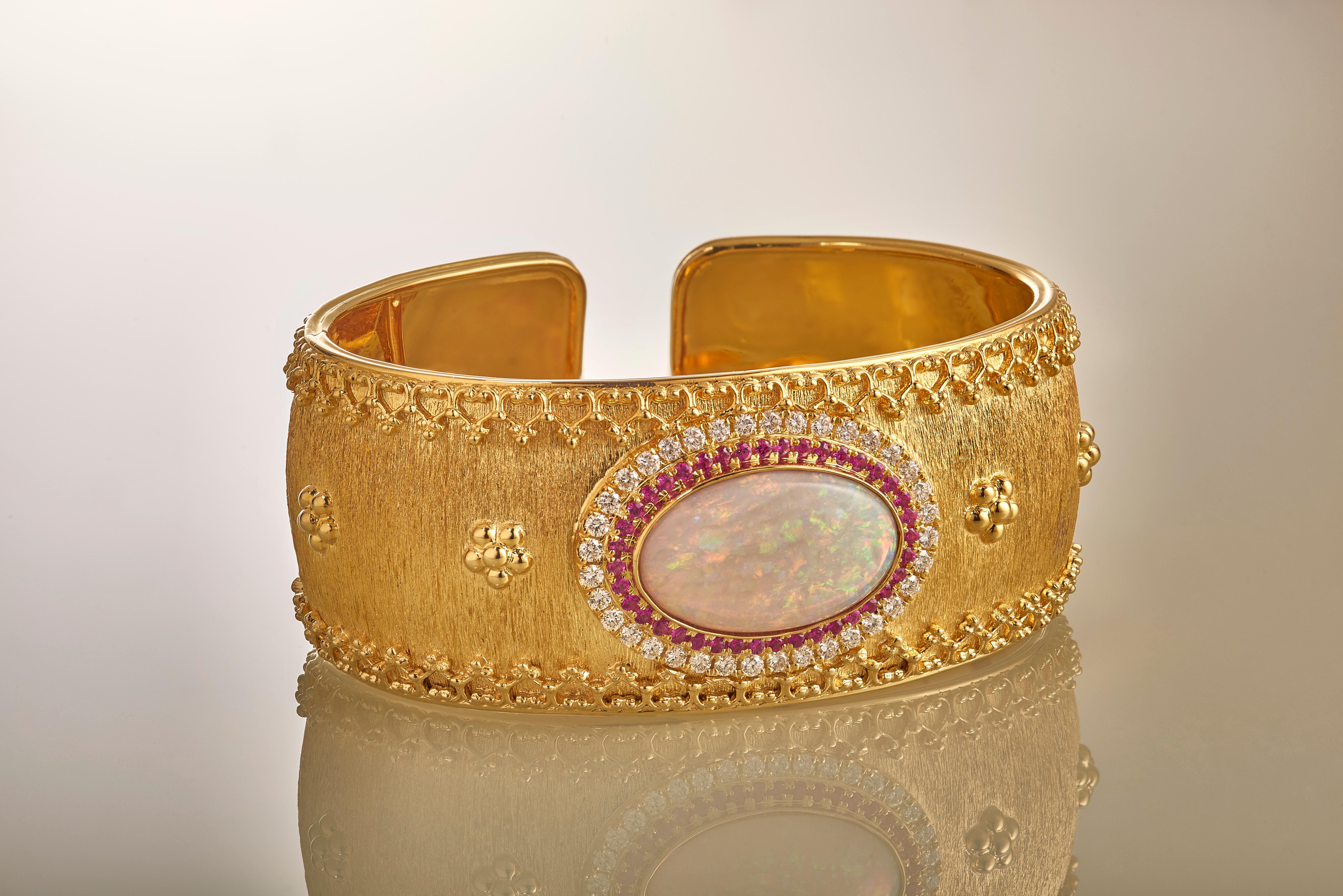 This one-of-a-kind, exquisitely detailed Etruscan style hinged cuff bracelet of 18k yellow gold, features an 8.3 carat solid Australian Coober Pedy Opal, surrounded by hand set brilliant white diamonds and vibrant pink rubies. This cuff has a