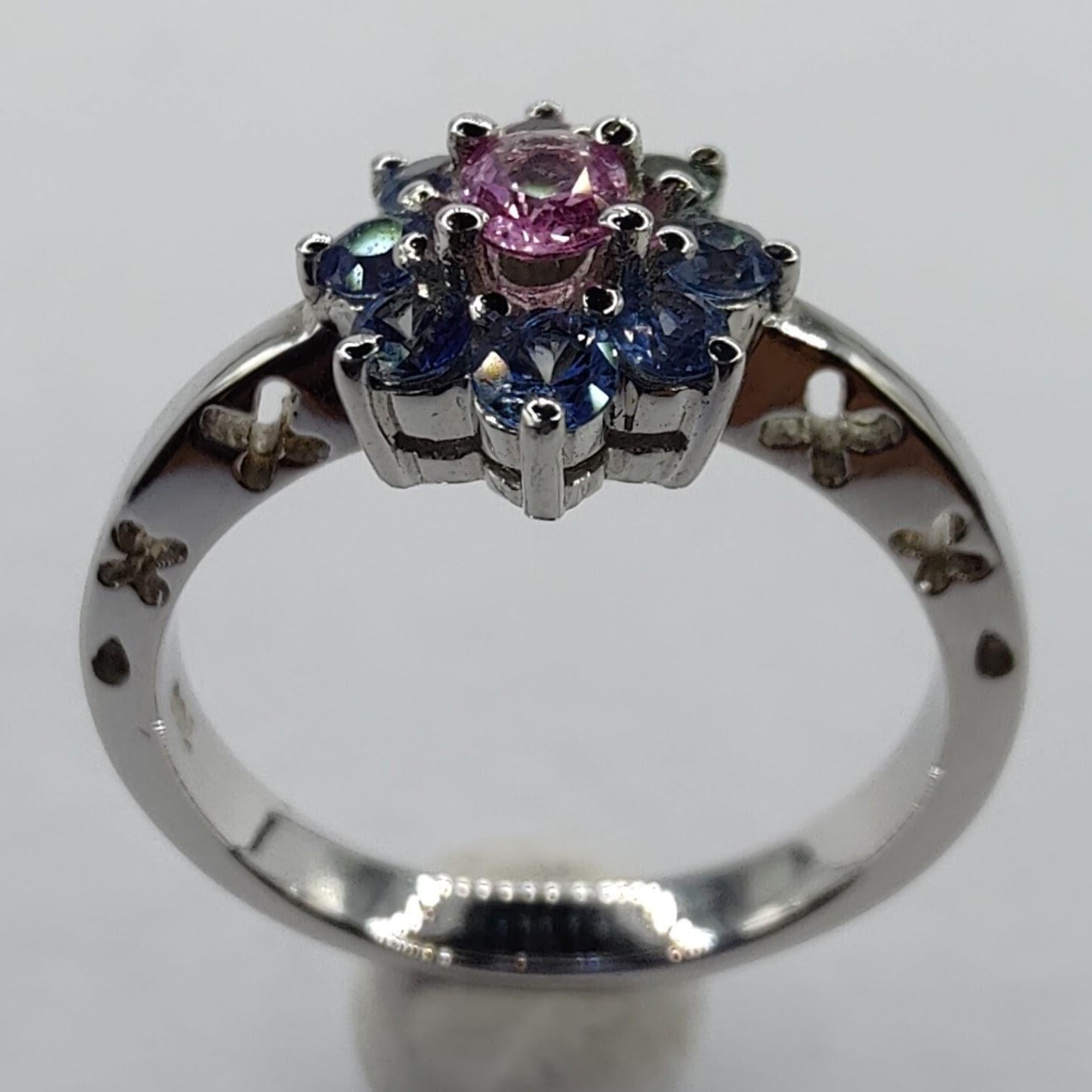 This stunning cocktail ring is the perfect choice for adding a pop of color and unique detail to your look. The ring features a beautiful flower design of 0.83 carats of sapphires, with an oval cut pink sapphire in the center, surrounded by a halo