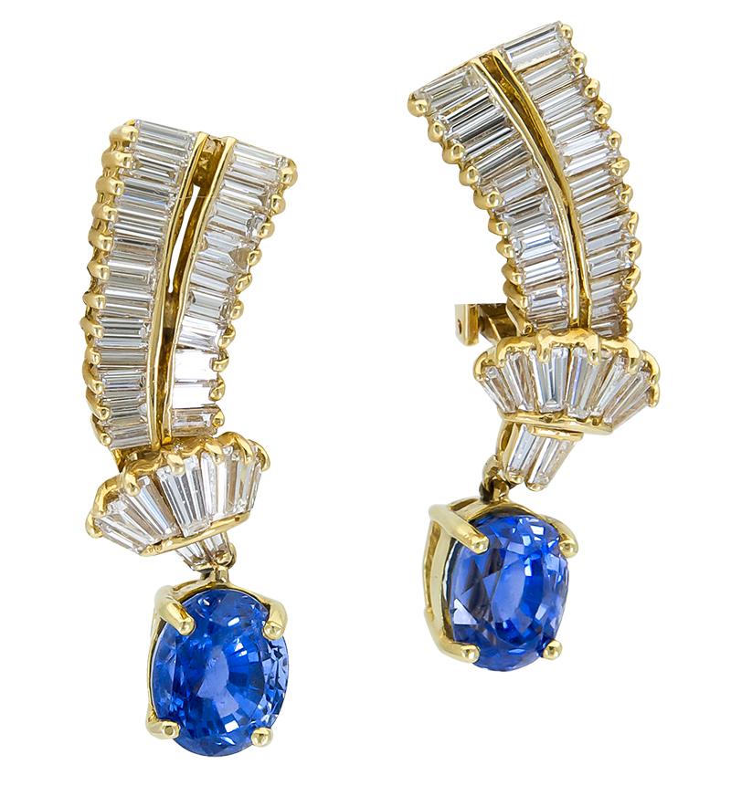 Each earring features an oval cut blue sapphire suspended on rows of step-cut baguette cut diamonds. Made in 18k yellow gold. Clip-on (no post). 
Blue Sapphires weigh 8.30 carats total.
Diamonds weigh 4.10 carats total. 
Gold weighs 15.50