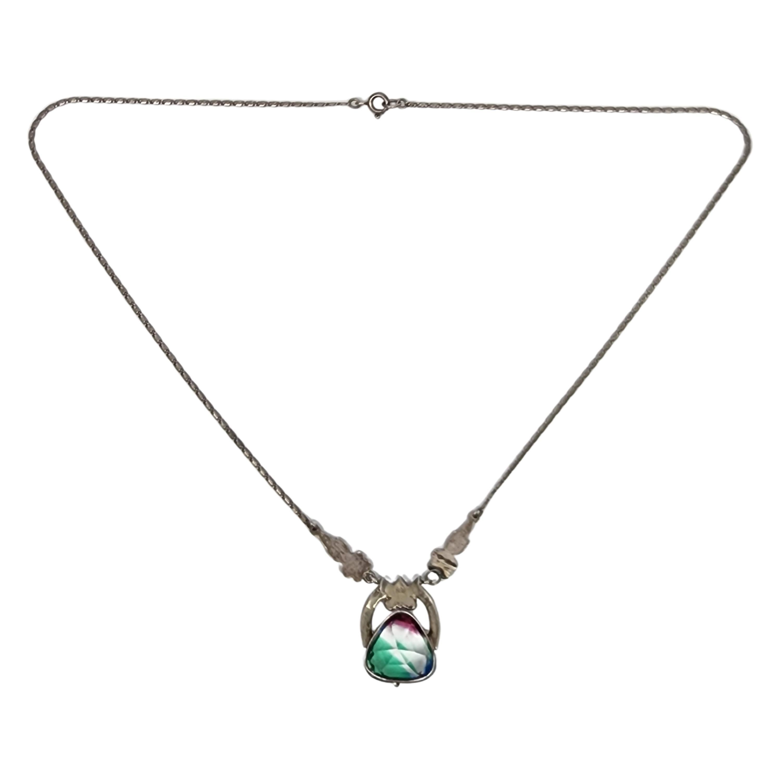 830 silver Iris Glass and marcasite pendant necklace.

A beautiful faceted iris glass triangle stone that features pink, blue and green colors. The stone is set in 830 silver with marcasite hanging from a coil link chain.

Weighs approx 6.5g, 4.2dwt