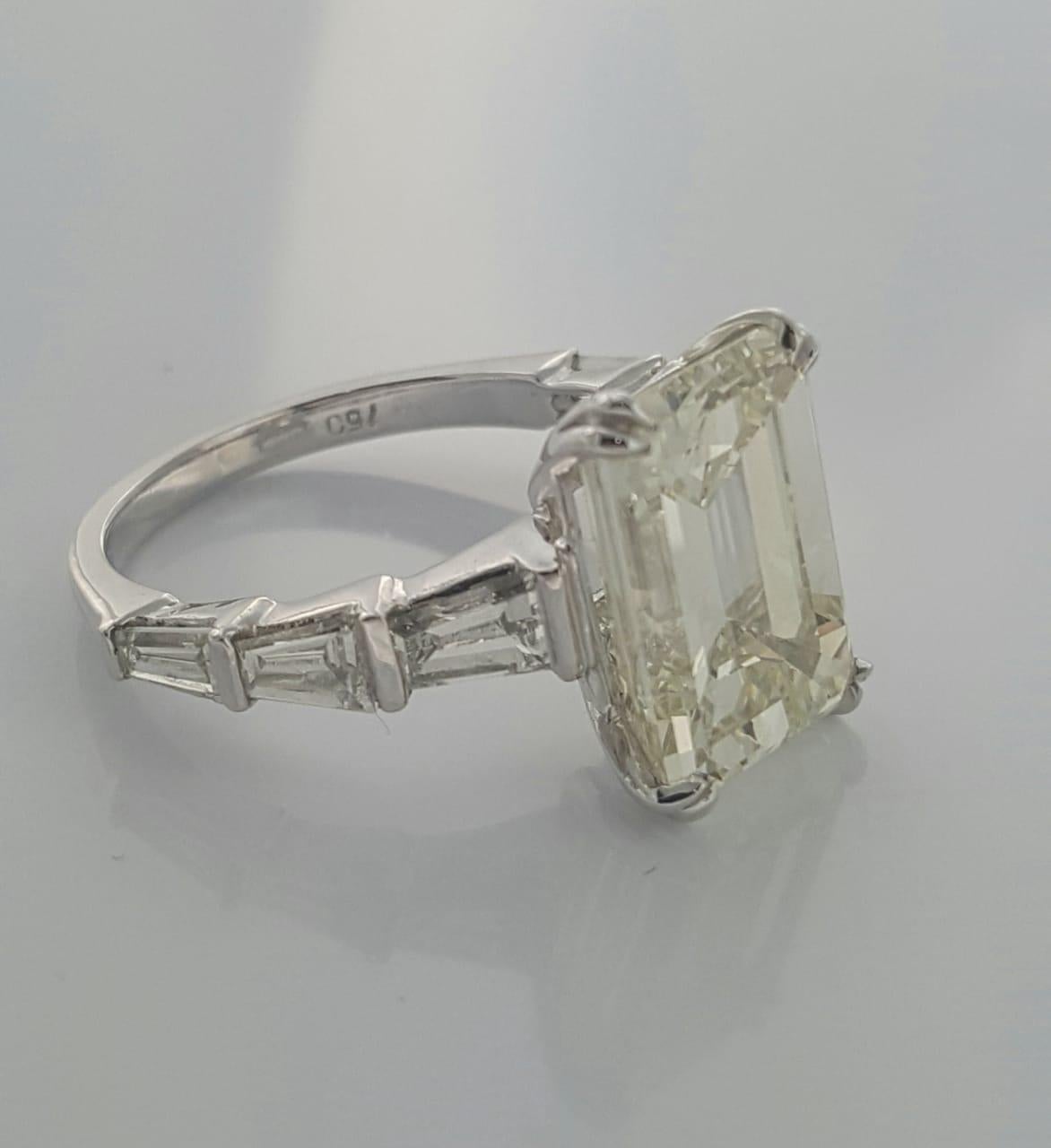A truly gorgeous engagement ring designed and handcrafted in 18k gold  by Moguldiam Inc features 7.01 carat Emerald cut diamond with M color and SI 1 clarity and  is flanked by 6 white baguette diamonds , 3 on each side with VS clarity weighing a