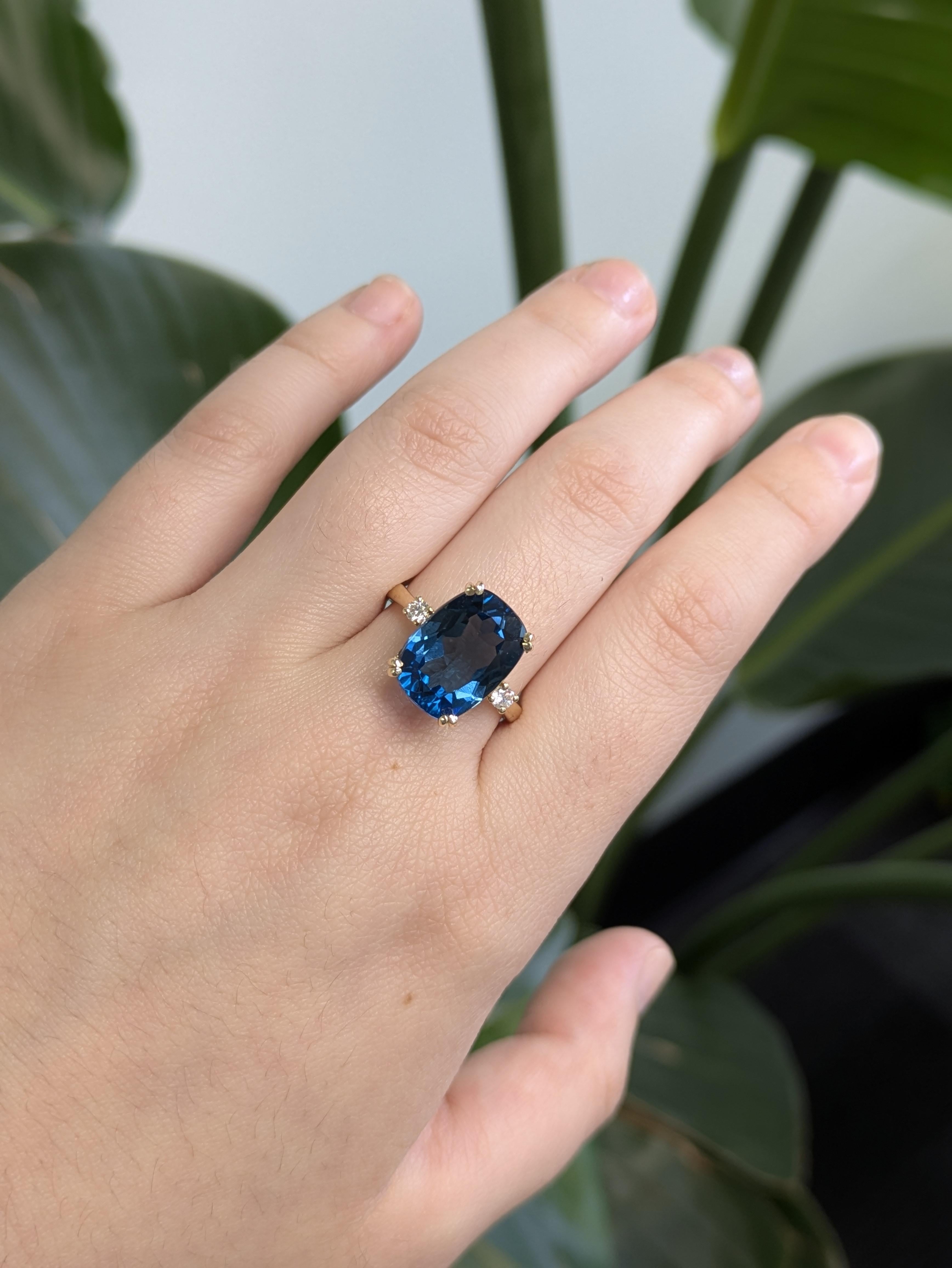 Uno splendido anello con topazio blu di Londra che mostra una ricca gemma dal taglio a cuscino che irradia profonde sfumature oceaniche. Con diamanti naturali e incastonati in oro giallo massiccio 14 carati, incarna un fascino senza tempo con un