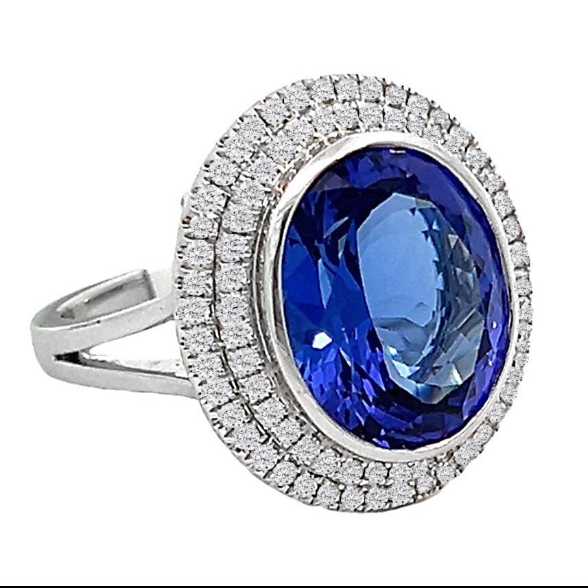 An impressive cocktail ring with an 8.40 carat bright blue oval tanzanite. The tanzanite weighs 8.40 carats and is bezel set in 18-karat white gold. The surrounding double halo of round brilliant diamonds elevates the brilliance and focuses on the