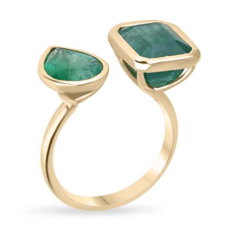 Dieser exquisite Ring von Toi et Moi zeigt zwei atemberaubende Smaragde - einen im Birnenschliff und einen im Smaragdschliff -, die beide durch ihren dunkelgrünen Farbton und ihre halbtransparente Klarheit bestechen. Jeder Smaragd ist elegant in