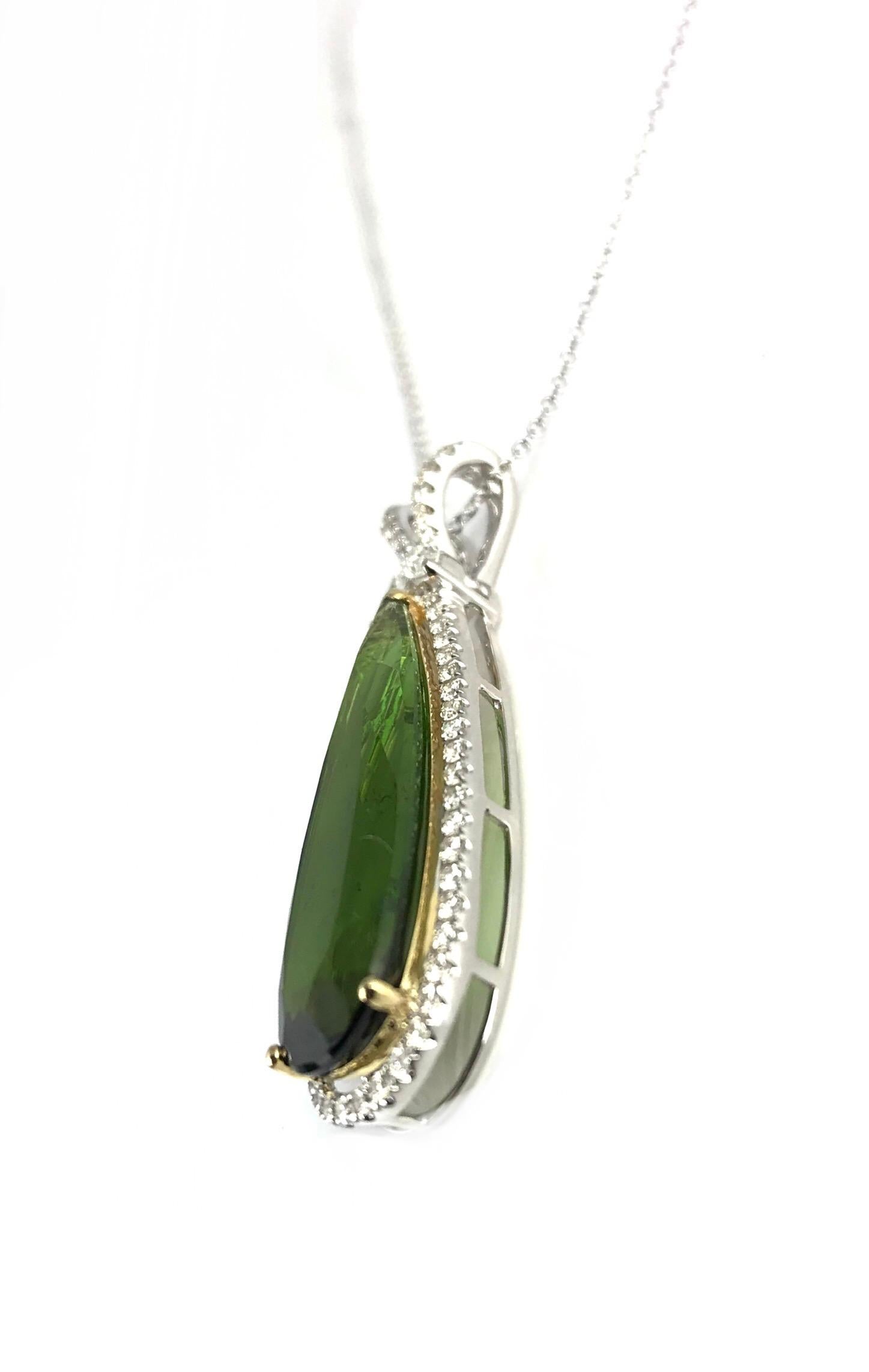 This unique pendant features an 8.44 carat extended pear shape kiwi green tourmaline, set in 18k white gold, with accents of 18k yellow gold at the prongs and in the delicate under gallery. A frame of round natural diamonds surrounds the center