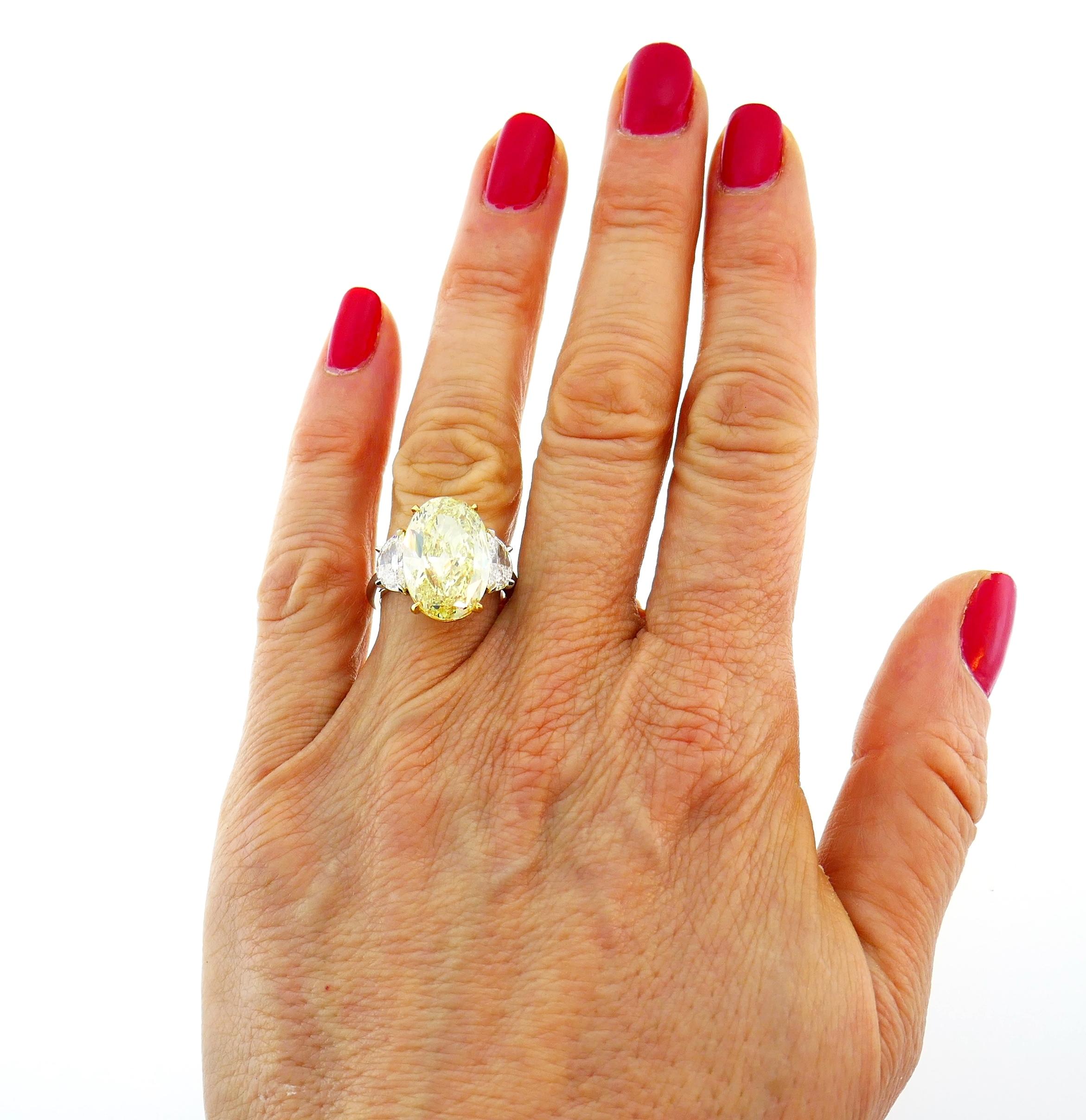 Magnificent and classy yellow diamond solitaire ring! Features a 8.47-carat natural fancy yellow oval brilliant cut diamond flanked by two half-moon cut white diamonds. The fancy yellow diamond comes with a GIA Colored Diamond Grading Report stating