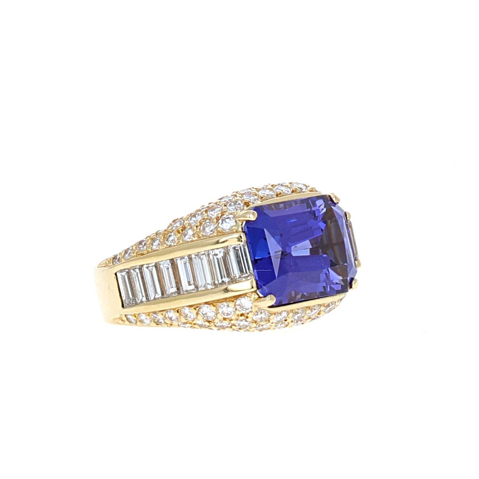 This 8.47 carat emerald cut tanzanite is set east-west giving it a trendy yet unique look. The tanzanite is set in an 18 karat yellow gold ring. The attention to detail makes this eyecatching mounting one-of-a-kind. Steming from the center gem are a