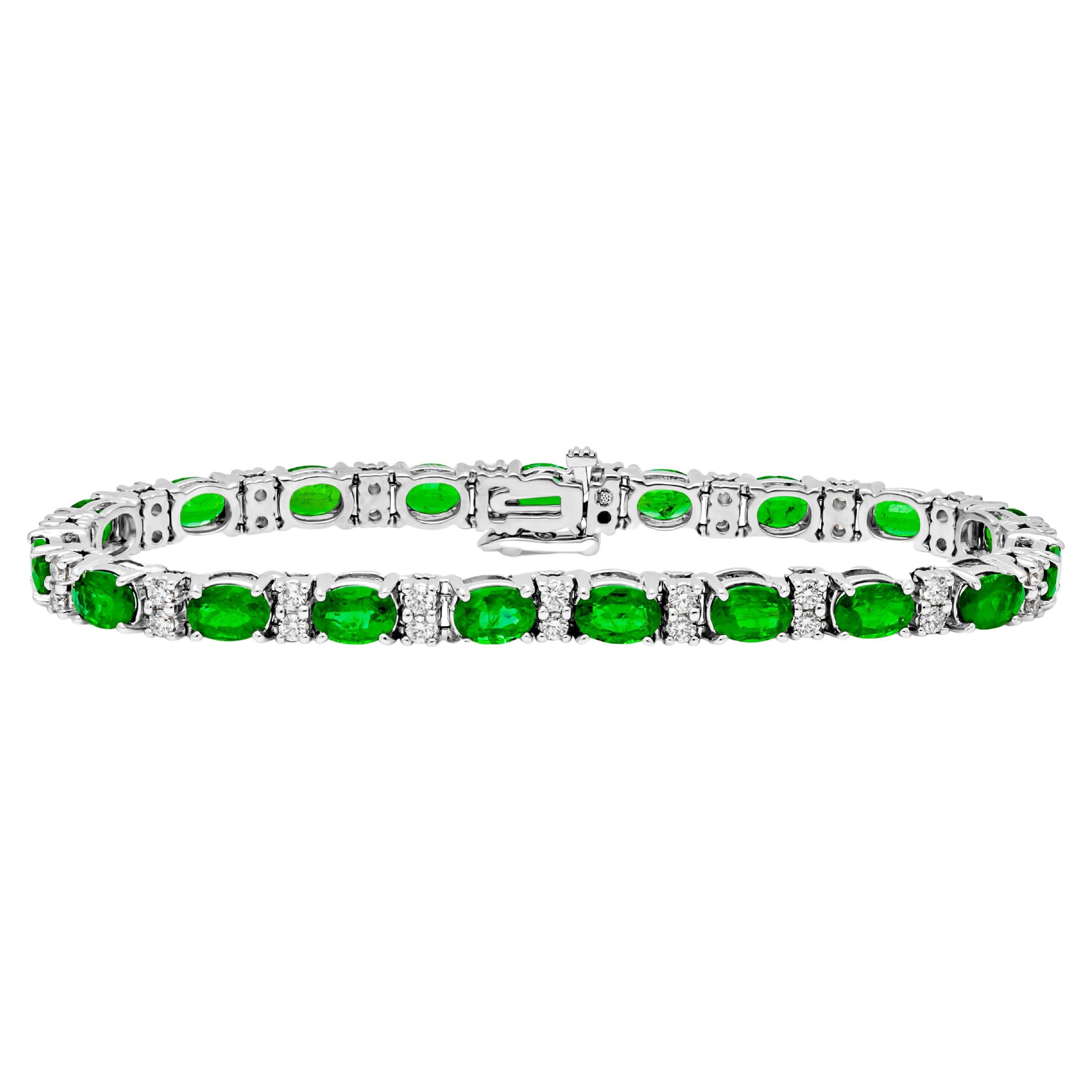 An exquisite and simple tennis bracelet, showcasing color-rich oval cut green emeralds weighing 8.48 carats total, set on a classic four prong basket setting finely made in 14K white gold. Evenly spaced by two melee round brilliant cut diamonds