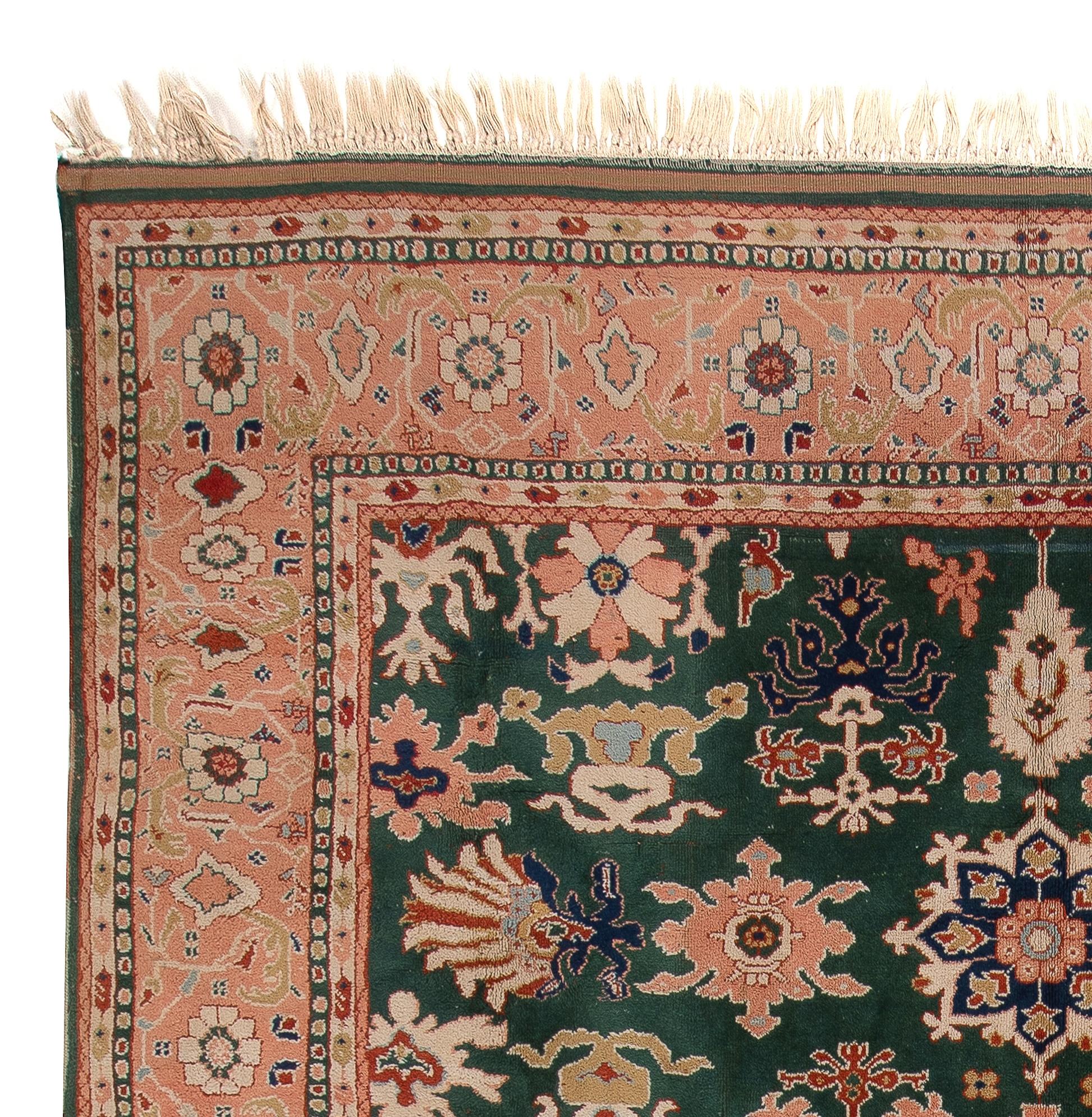 This exquisite hand-knotted Turkish rug features a beautiful color palette of glowing peach and deep, dark emerald green which together create a soft, delightful contrast and give off a sense of warmth. Its field is densely decorated with free