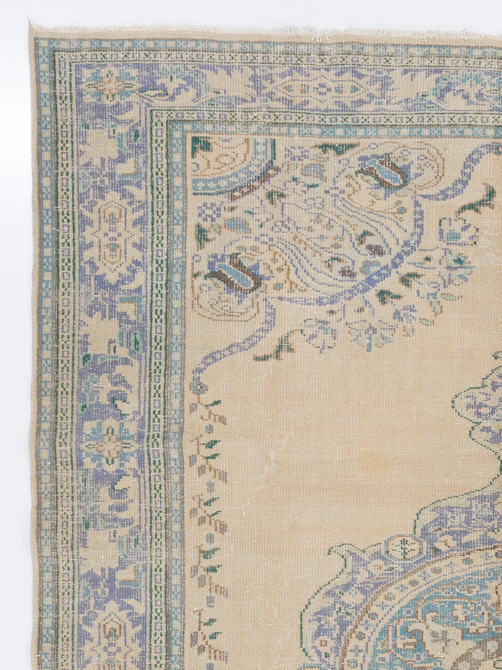 A finely hand-knotted vintage Turkish carpet from 1960s featuring a central medallion in slightly washed out purple, blue and brown against a plain field in soft, glowing beige as well as floral corner pieces, finely detailed inner and outer guard