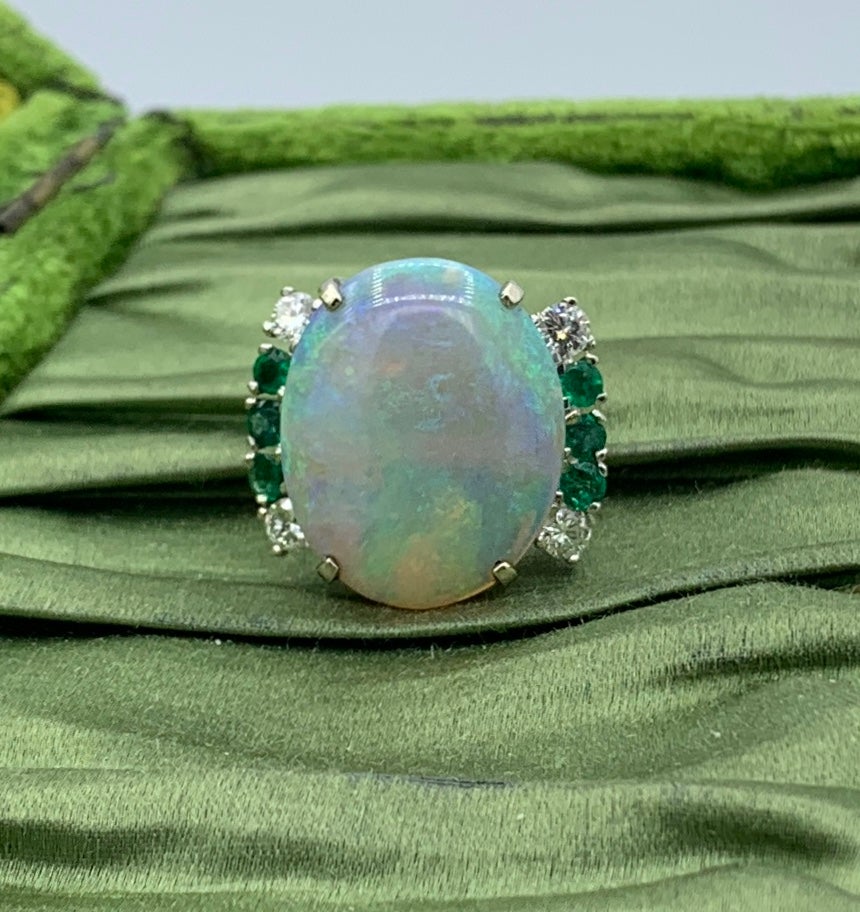 Il s'agit de l'une des plus belles bagues monumentales 8,5 Carat Opal Diamond Emerald Rings que nous ayons vues.  L'extraordinaire opale ovale en cabochon a des reflets bleus, verts, rouges, jaunes et orange.  L'opale est un cabochon ovale d'environ