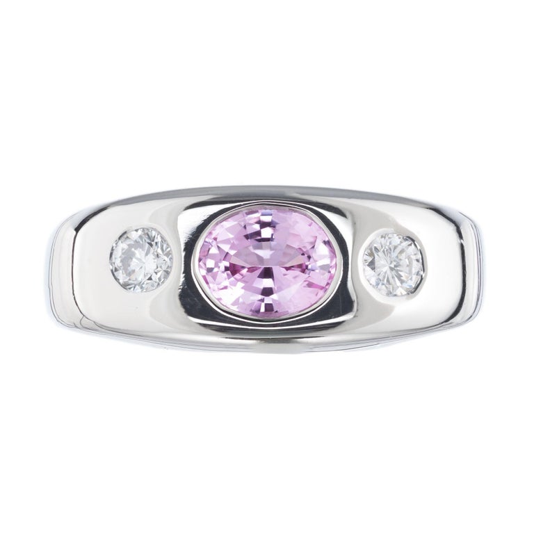 Natural pink sapphire and diamond gypsy three-stone ring. GIA certified oval bright soft pink center sapphire with two full cut side diamonds in a 14k white gold setting. All three stone sit flush with the setting. 

1 oval light bright soft pink