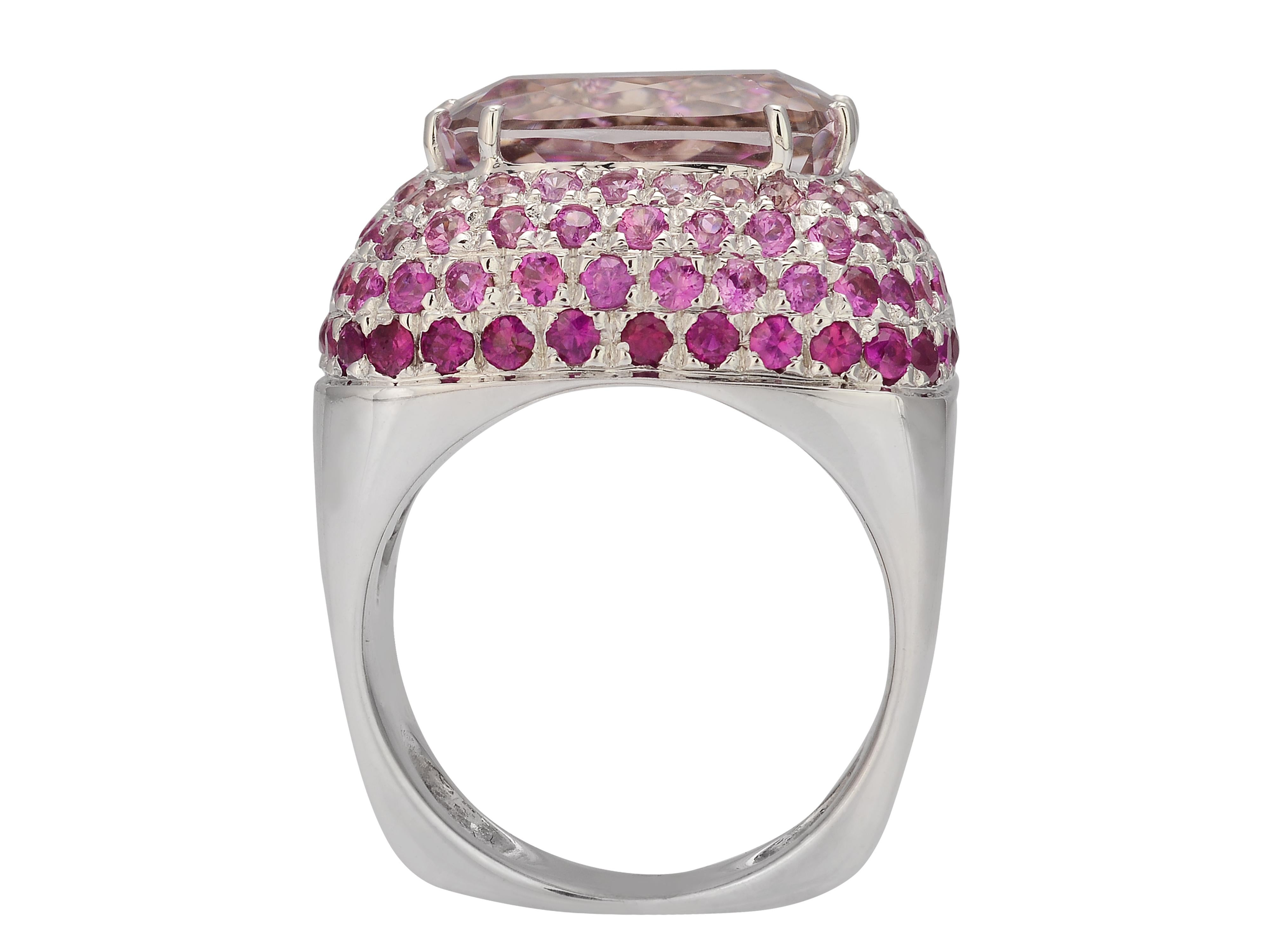 18 karat white gold wide cocktail ring featuring a prong-set 8.50 carat Kunzite center stone. The kunzite is surrounded by 114 pave-set pink sapphires and rubies totaling 3.50 carats. Finger size 7; purchase includes ring sizing.