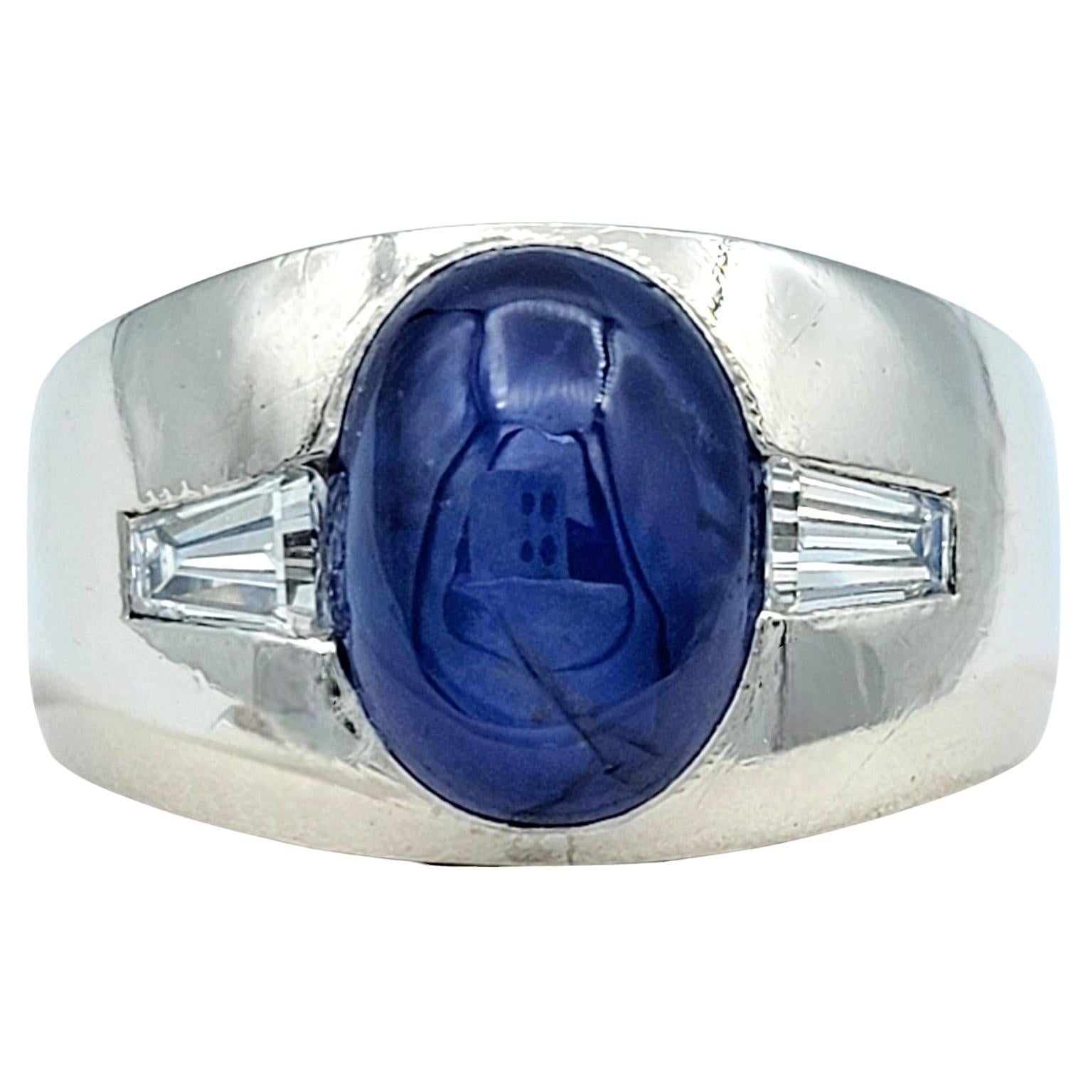Ring size: 9.5

This striking unisex wide band ring, crafted in sleek platinum, features an extraordinary 8.50 carat oval cabochon star sapphire as its centerpiece. The mesmerizing star sapphire showcases a captivating celestial effect, drawing the