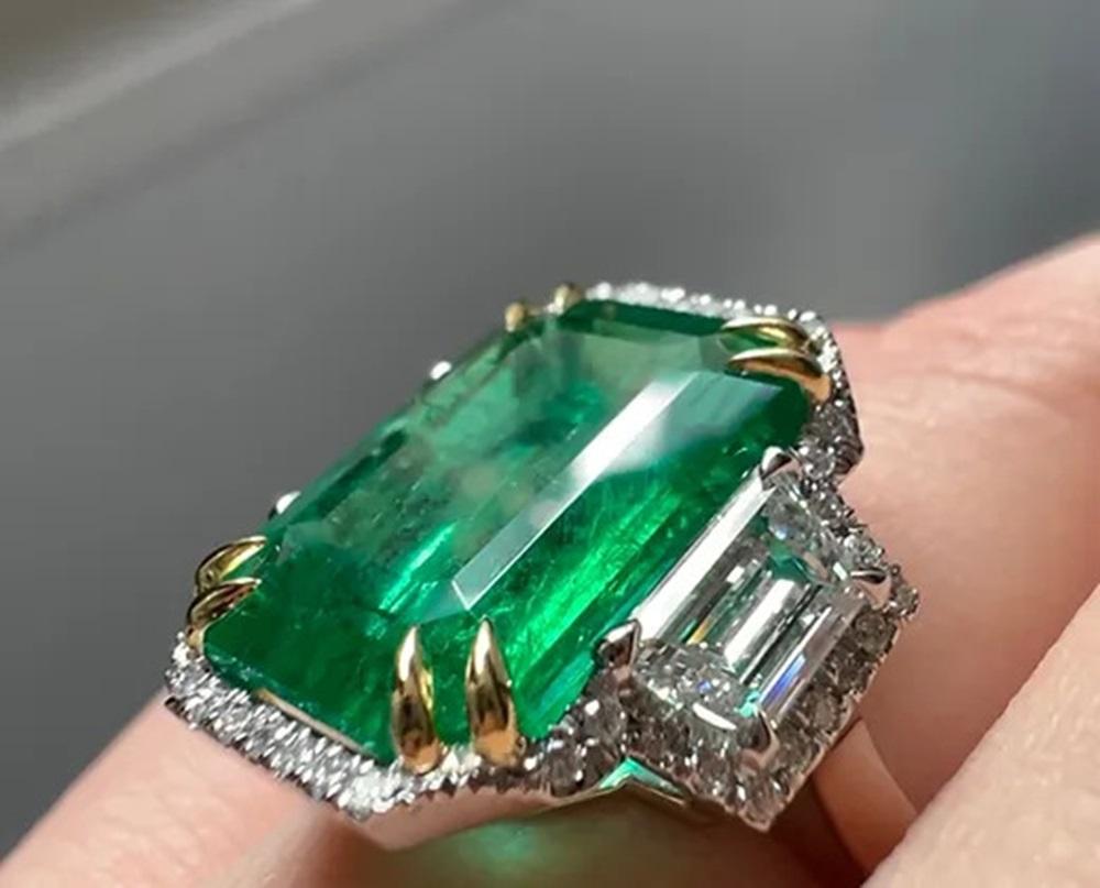 Emerald Weight: 8.55 CTS, Measurements: 14.93 x 10.95 x 6.39 mm, Diamond Weight: Trapezoid side stones 1.17 CTS (E-VS), halo 0.17 CT, Metal: Platinum/18K Yellow Gold Basket Gold, Weight: 8.94 gm, Ring Size: 7, Shape: Emerald-Cut, Color: Intense