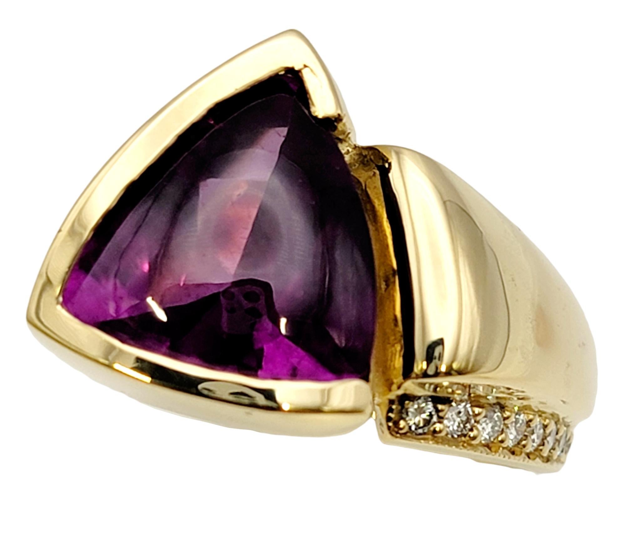 Ring size: 6

Bold and contemporary gemstone ring featuring a large triangular buff top rhodolite garnet and accented with natural white diamonds. This sizeable piece features an asymmetric design in polished 18 karat yellow gold. The bright,