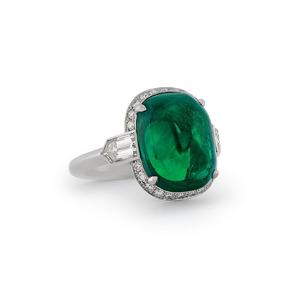 Stunning cabochon emerald and diamond ring by Hancocks, centred with a wonderful sugar loaf cabochon cut Colombian emerald weighing 8.59cts and claw set within a fine halo surround of single cut diamonds between shoulders set with bullet cut