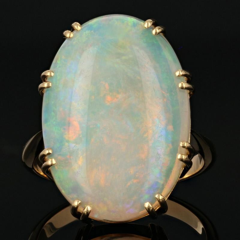 This ring is a size 7.

Metal Content: Guaranteed 18k Gold as stamped

Stone Information: 
Genuine Opal
Cut: Oval Cabochon
Size: 21.1mm x 14.6mm
Carat: 8.60ct 

Style: Cocktail Solitaire 
Face Height (north to south): 27/32