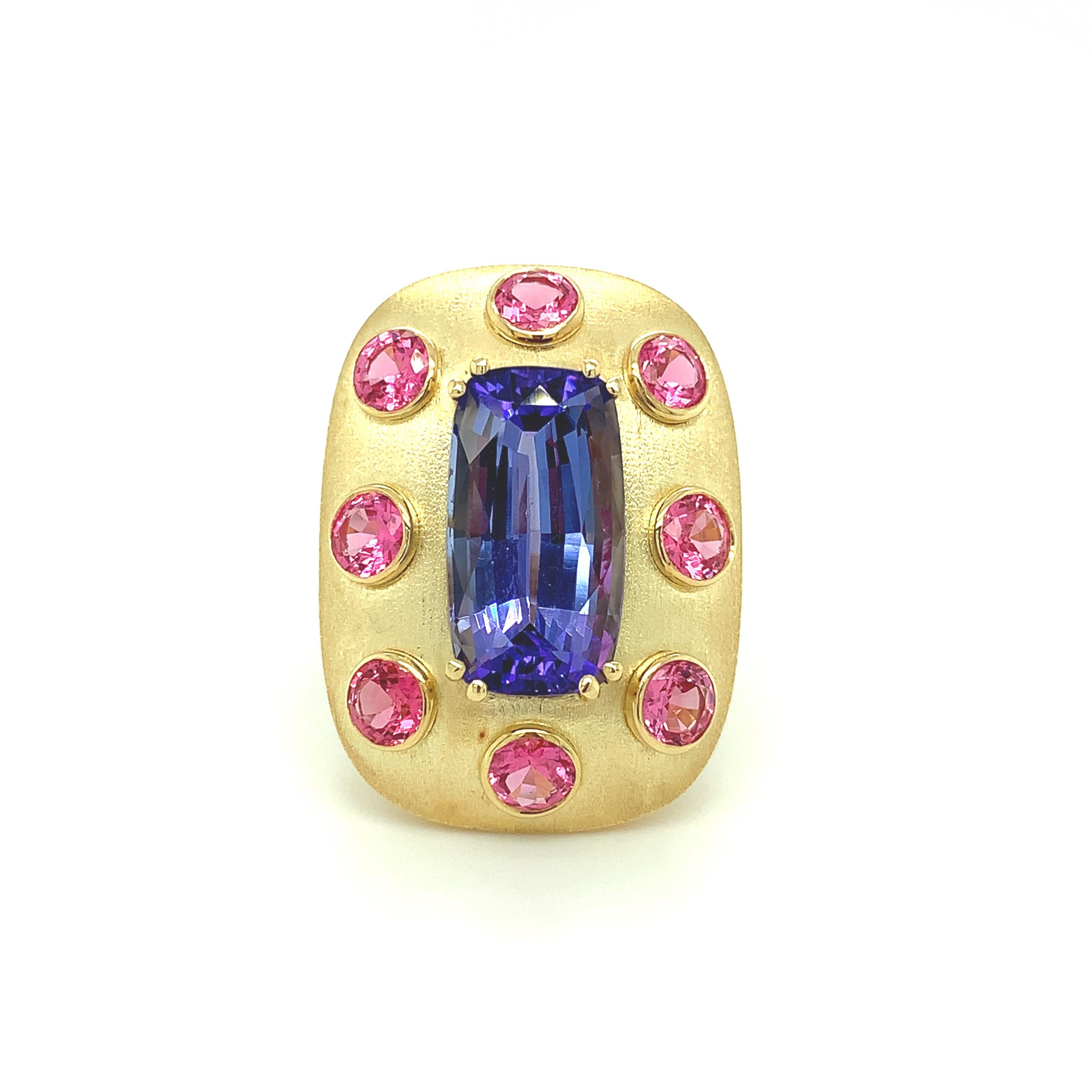 A beautiful, 8.61 carat cushion cut tanzanite and vivid, round pink spinels are set in this handmade 18k yellow gold ring. The tanzanite is a vibrant, lavender-blue color - a perfect complement to the bright, fuchsia-pink spinels! This ring was