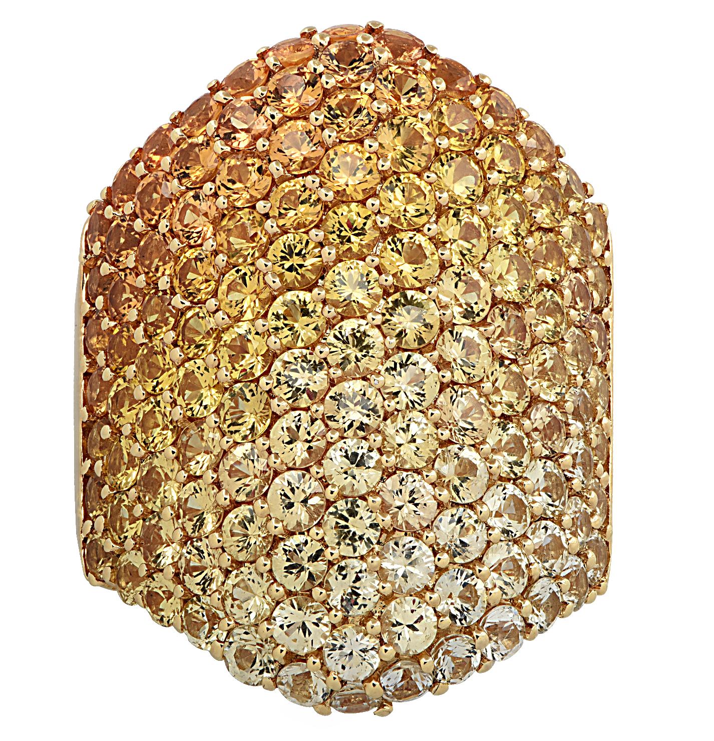 Striking cocktail ring finely crafted in 18 karat yellow gold, featuring round sapphires weighing approximately 8.64 carats total, saturating in color from very light yellow to vivid yellow and orange. The gemstones are pave set, blending in shades