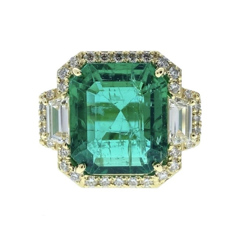 The ring is set in 18k yellow gold, and the main emerald is an emerald-cut with a substantial weight of 8.70 carats. Additionally, the ring features green diamonds as side stones, with a round cut and a total quantity of 32, weighing approximately