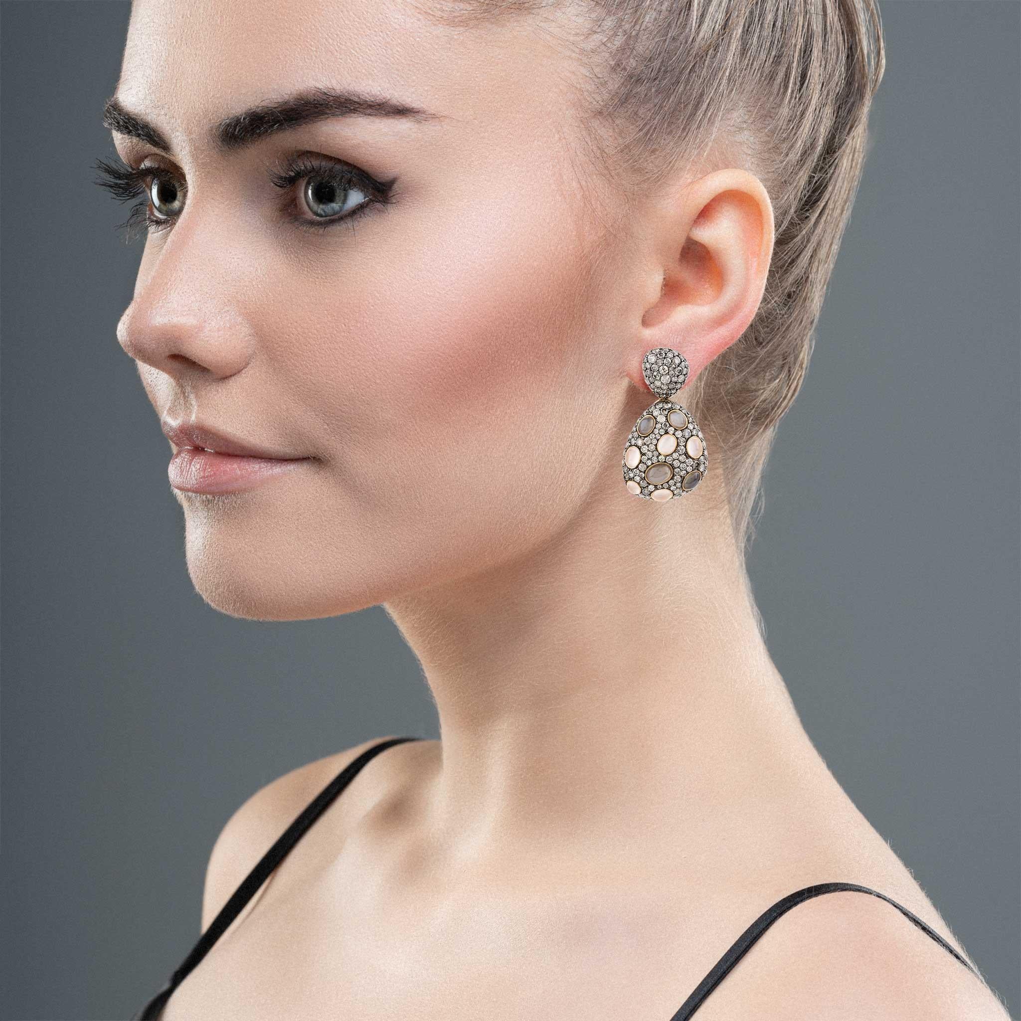 These exquisite earrings are crafted from 18 karat rose gold, adorned with 18 rare cat's eye moonstones totaling 5.84 carats, each possessing a unique and mesmerizing shimmer. Surrounding these moonstones are 288 round cut diamonds, adding a