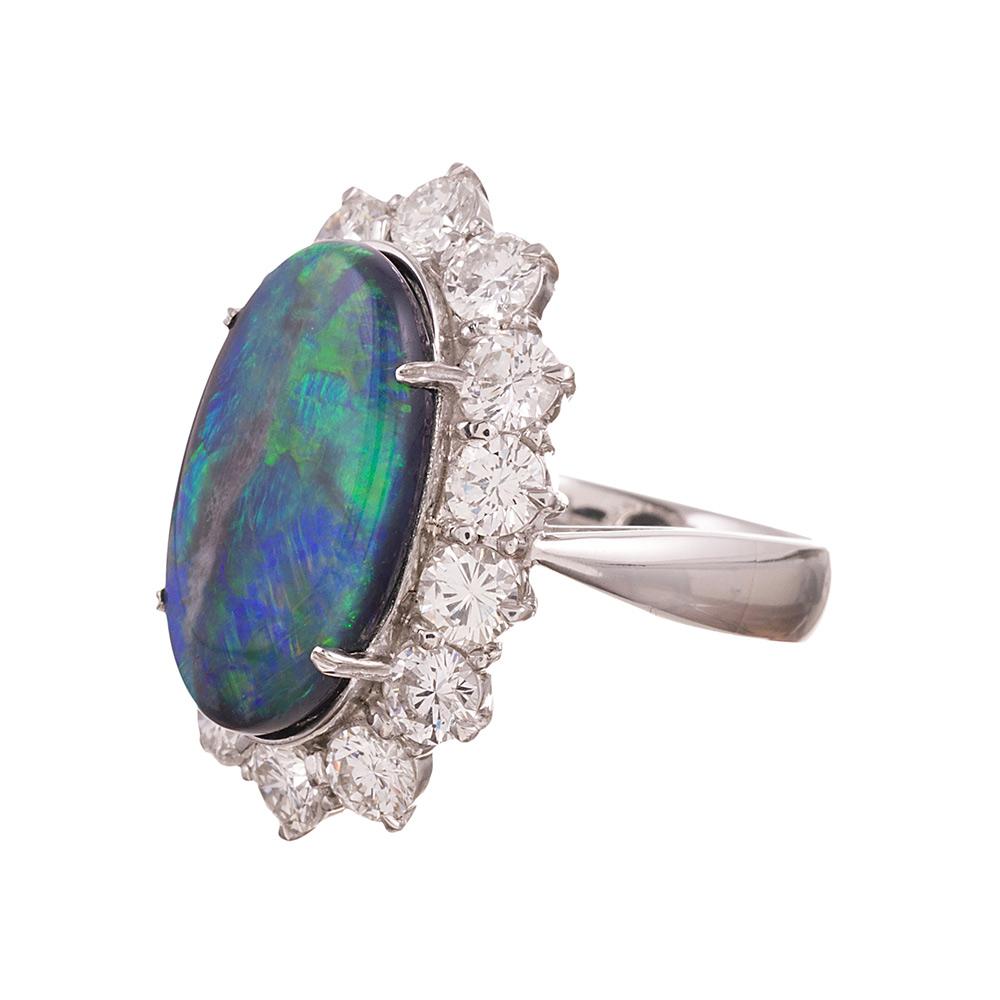 A striking oval opal, with strong flashes of blue and green, framed in a bright border of brilliant white diamonds. The stone is set in a handmade heavy platinum mounting. The diamonds weigh 3.33 carats in total. Size 7.25 can be resized on request.