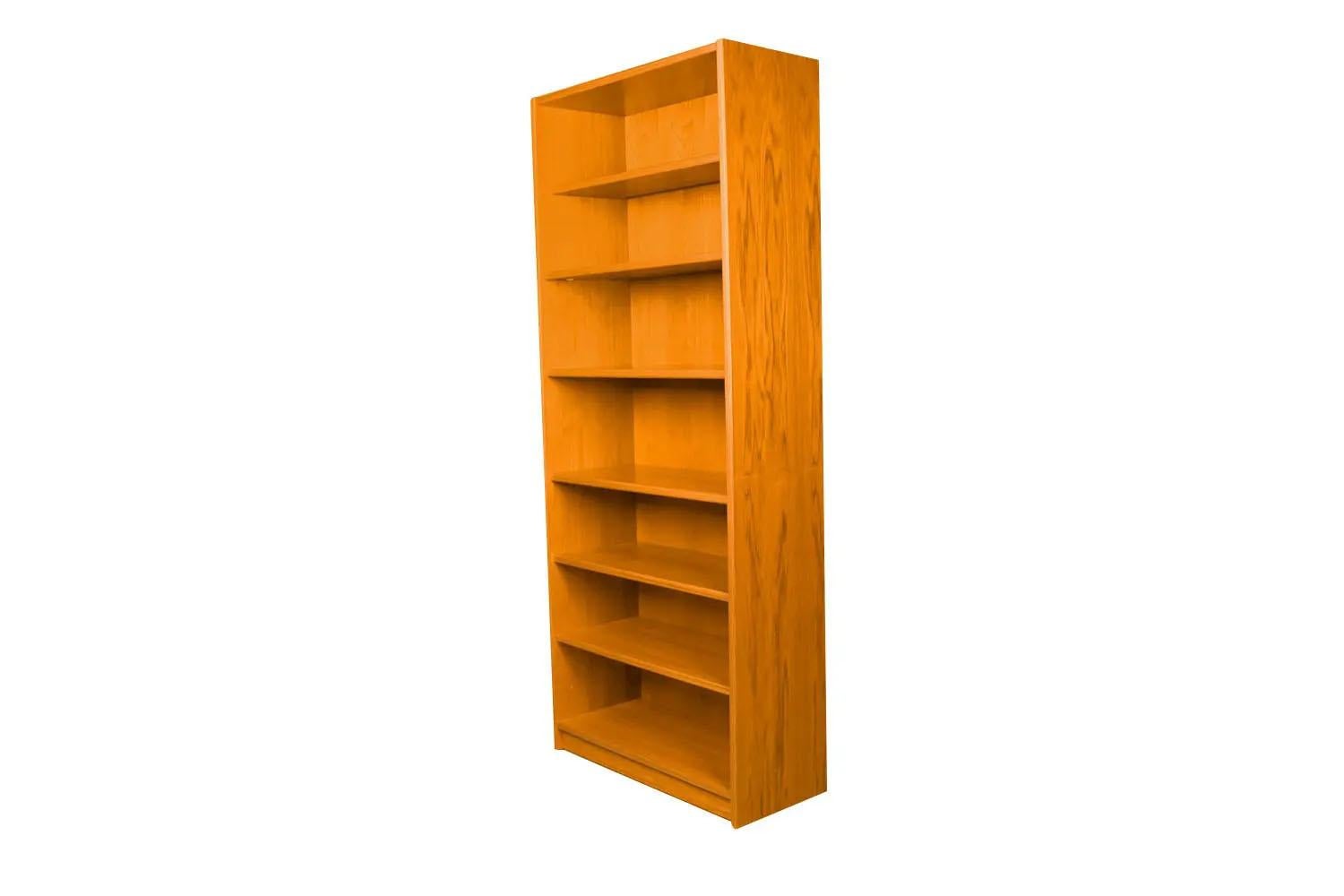 An exceptional teak tall bookcase made in Denmark. Gorgeous Mid-Century Modern Teak bookcase / tall bookshelf unit. Beautiful, minimalist, clean, straight lines. Features five and one stationary providing ample storage space. The top shelf is 11?
