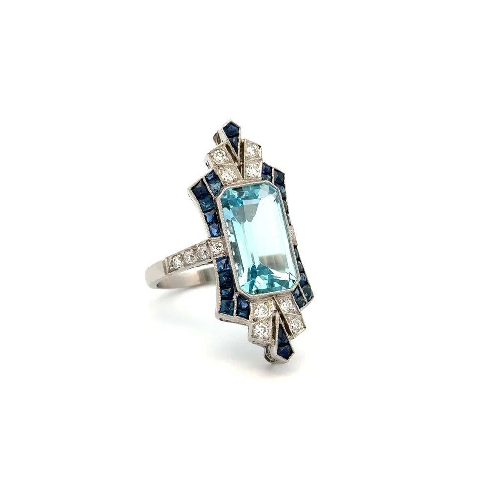 Sencillamente hermoso Anillo de cóctel en platino con aguamarina, zafiro y diamantes OEC. Centra una aguamarina talla esmeralda de 8,89 quilates engarzada a mano de forma segura. Rodeada de zafiros engastados a mano con un peso aproximado de 1,50 qt