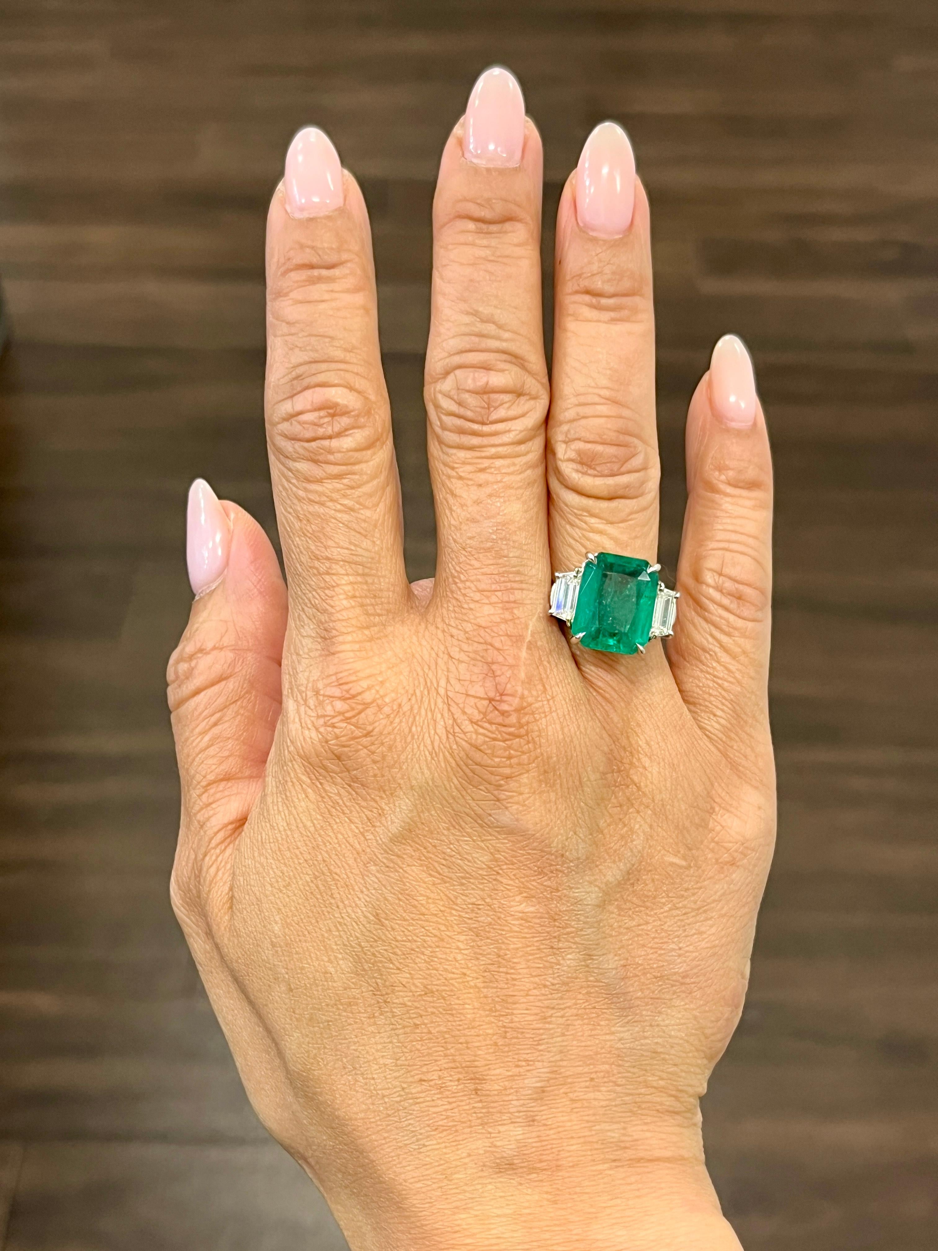 This gorgeous natural emerald and diamond ring is sure to turn heads. The 7.60 ct natural emerald is encased in platinum and sits right in the center of the ring. Two trapezoid diamonds hug the center stone, the diamonds have a color of G/H and are