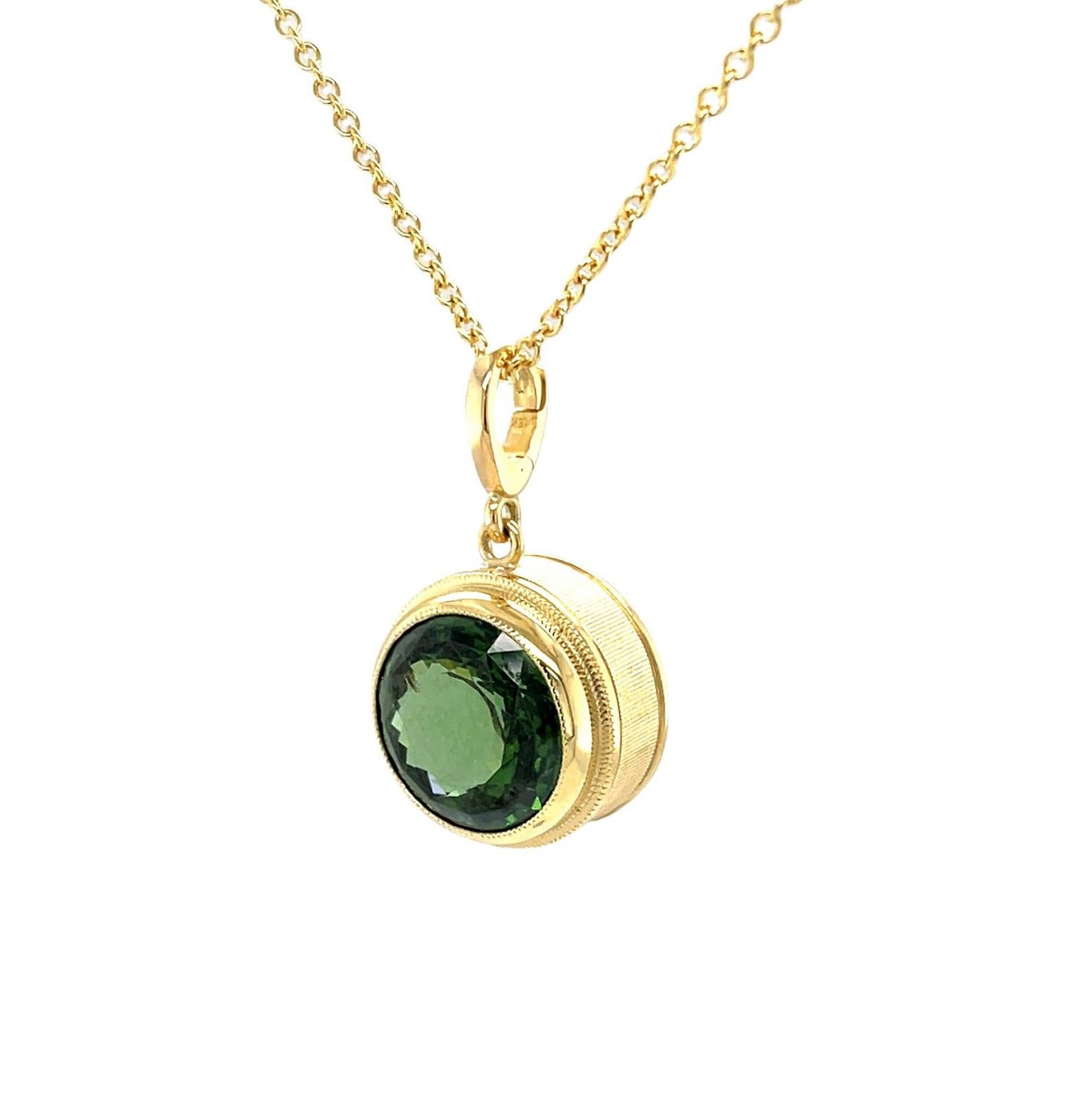 This stunning enhancer pendant features a gorgeous, 8.94 carat round green zircon, set in a custom-designed, hand engraved 18k yellow gold bezel. Zircon is December's birthstone and comes in a rainbow of beautiful color. This green zircon is of