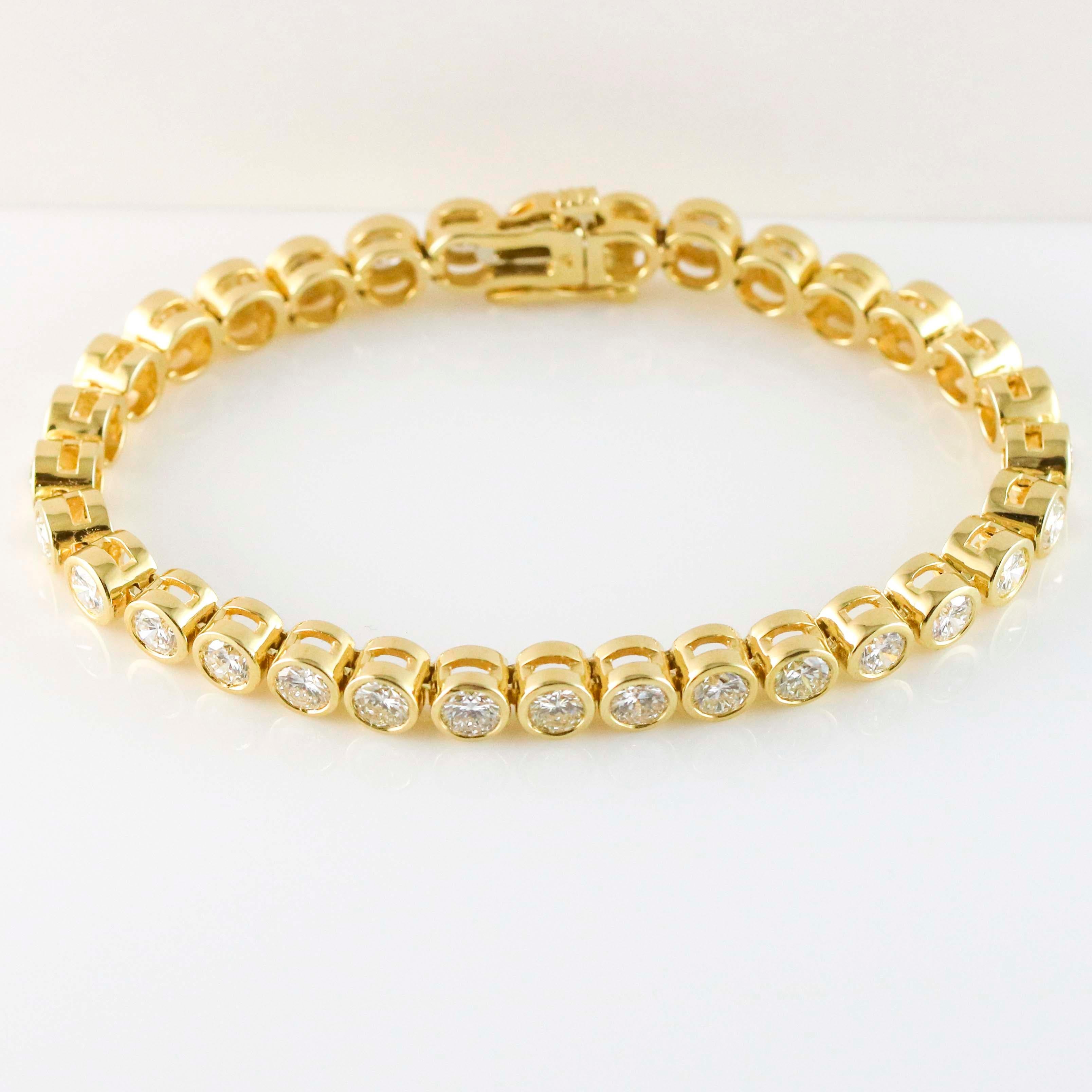 In-line diamond tennis bracelet crafted in 14k yellow gold. The bracelet is bezel-set with 32 round brilliant cut diamonds. Safety slide clasp. Diamonds, VS-SI G-I. Weight, 21.9 grams.