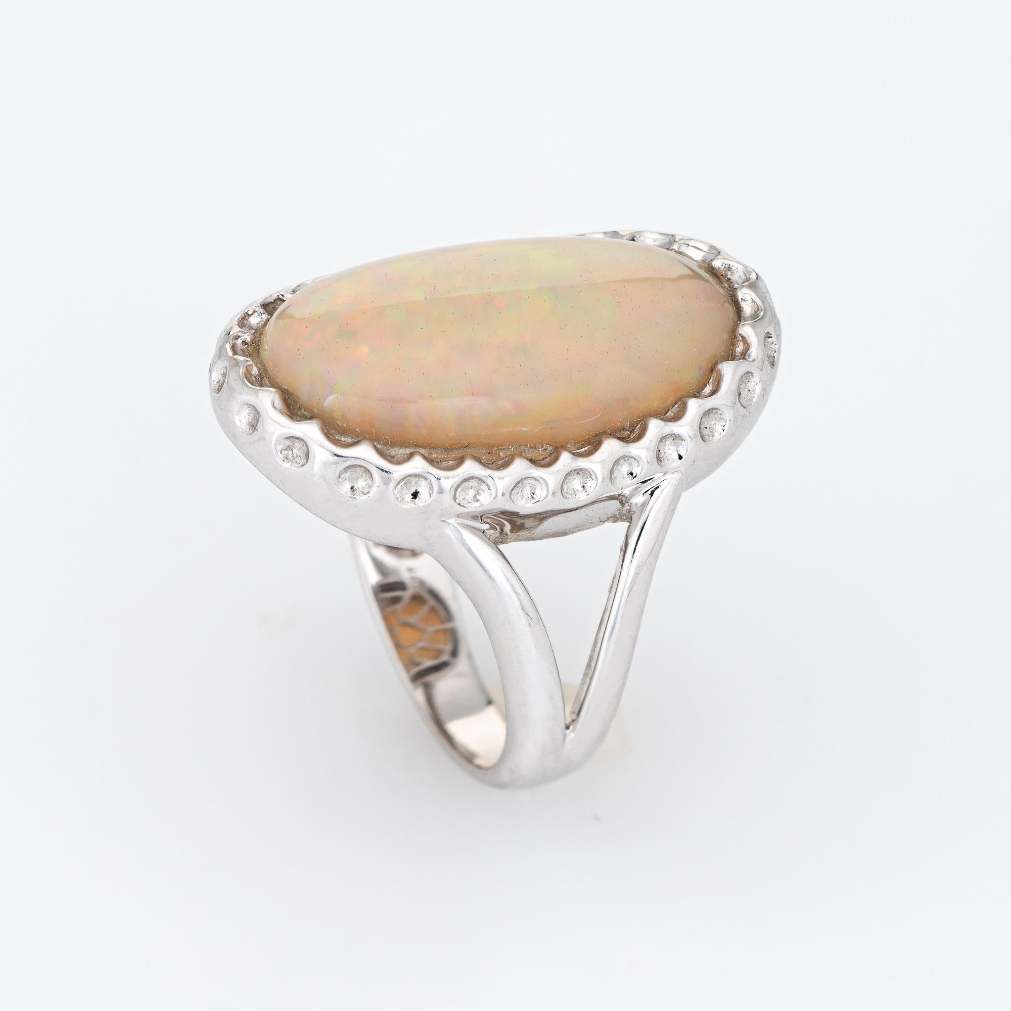 Élégante bague cocktail en or blanc 14 carats, ornée d'une opale naturelle de 8 carats.

L'opale naturelle taillée en cabochon mesure 20 mm x 12 mm (estimée à 8 carats). L'opale est en excellent état et ne présente ni fissure ni éclat. 

L'opale