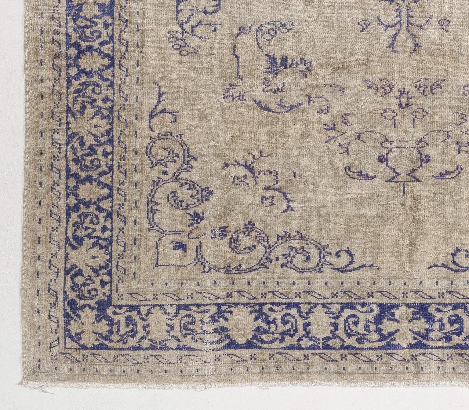Ce tapis d'Anatolie centrale, finement noué à la main, présente un motif de médaillon clairsemé et de vignes flottantes en bleu marine sur un fond de couleur kaki. Il accompagnera parfaitement vos intérieurs grâce à son aspect antique et