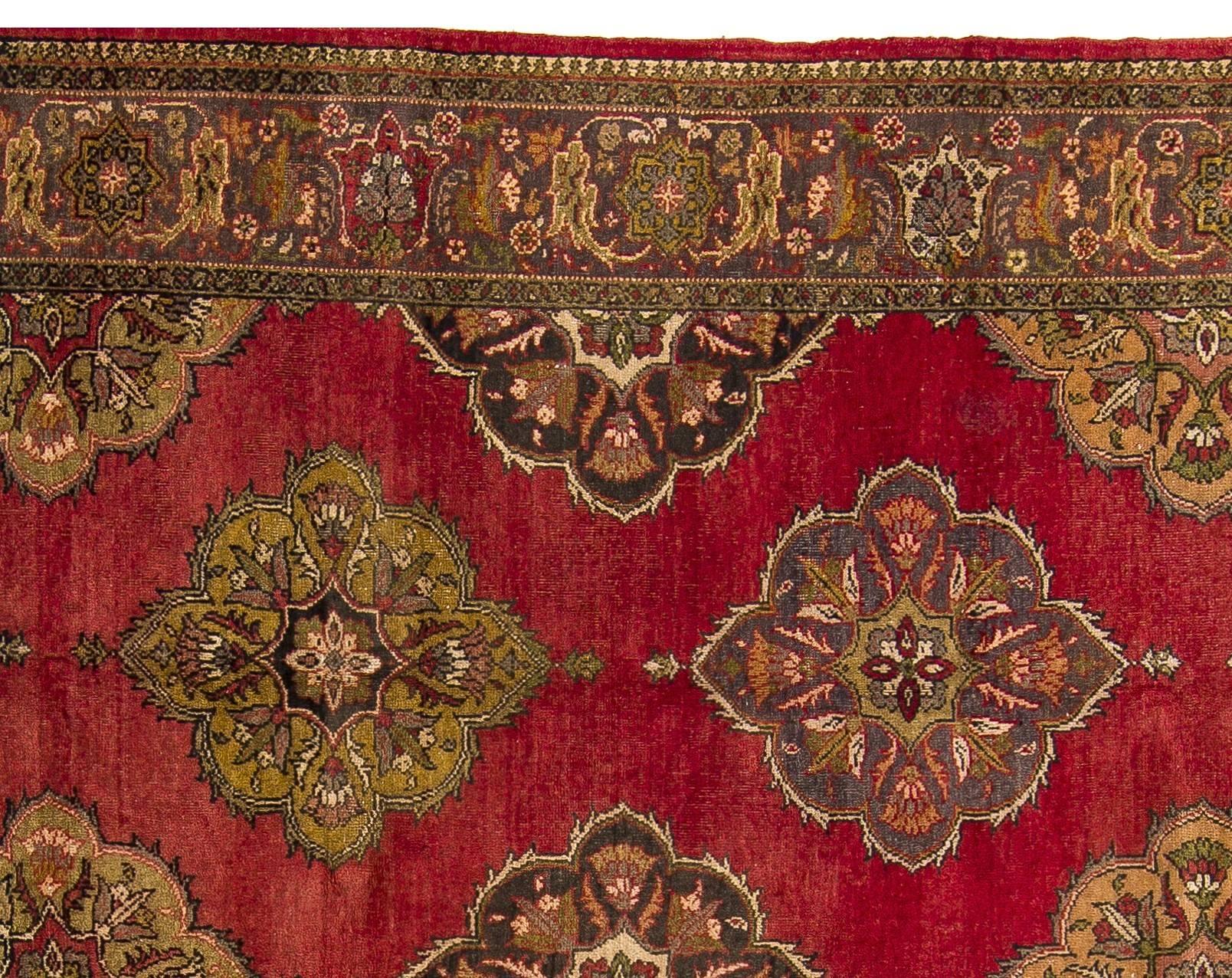 A large, decorative Oushak wool rug hand-knotted possibly by Greeks of Anatolia in the first half of the 20th century. It features a design of curvilinear, octagonal medallions in chartreuse and bluish gray in multiple rows across the length of a