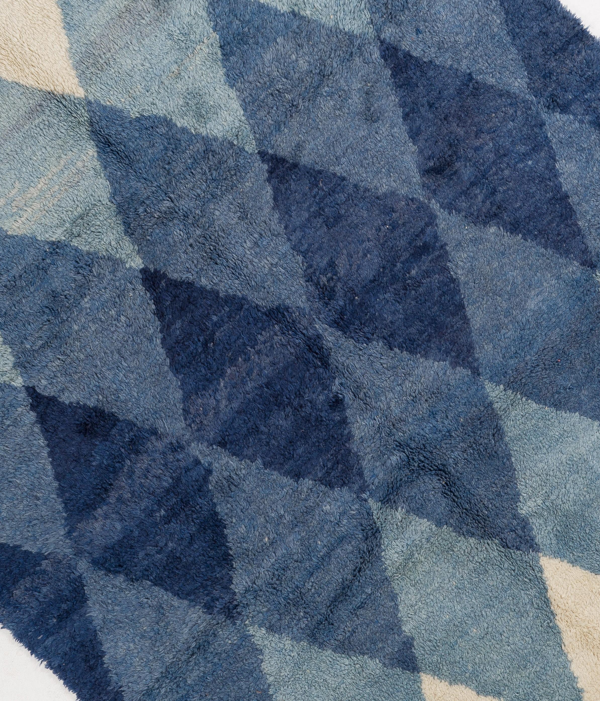 Un exquis tapis marocain tout neuf, noué à la main à partir de laine de mouton fine filée à la main, avec un motif géométrique audacieux dans de belles nuances de bleu indigo sur un fond crème. Une véritable pièce d'apparat qui peut facilement