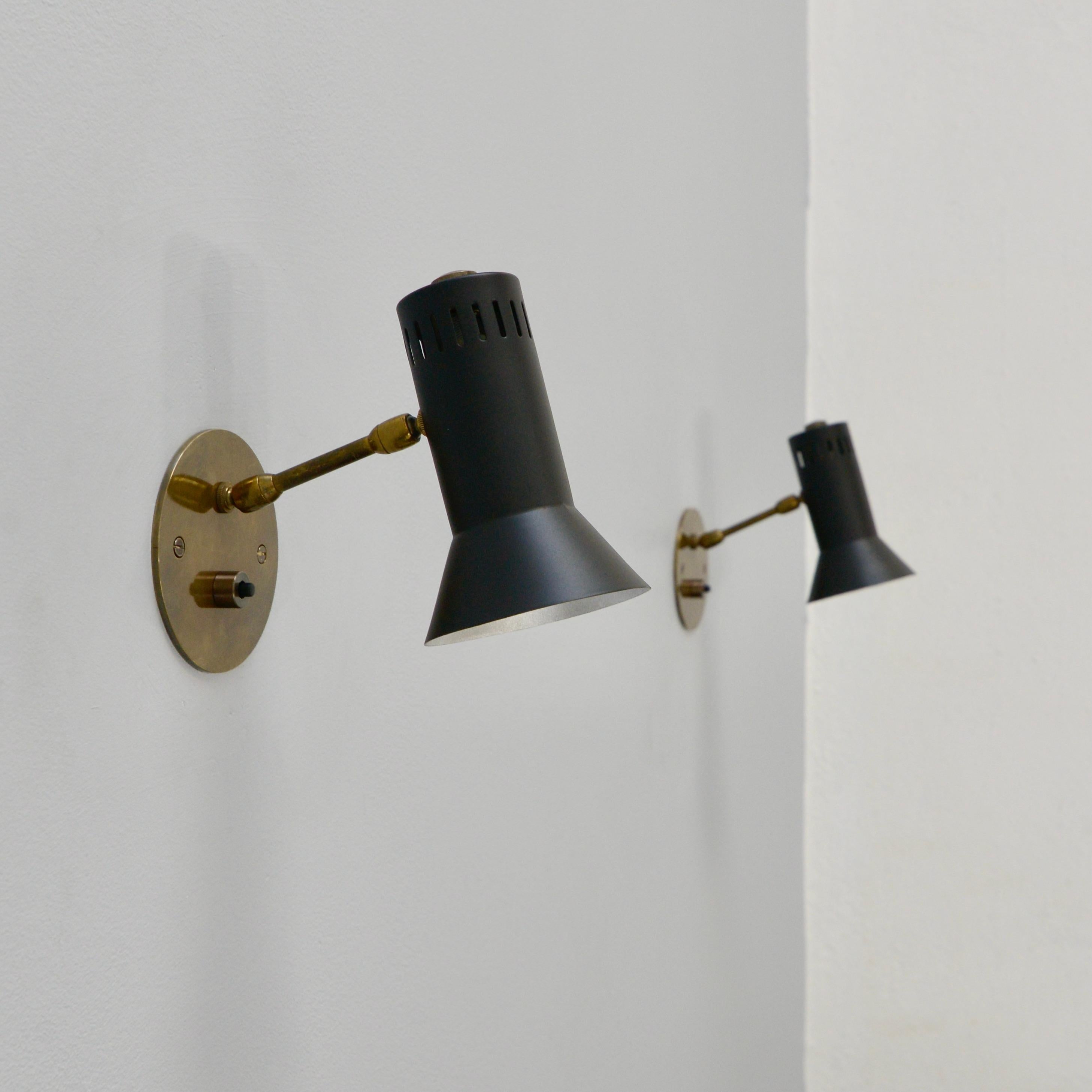 (7) partially restored aged brass and painted aluminum directional sconces from 1950s Italy. Arm and shade articulate in multiple directions. Slotted perforations allow for rich light quality. Wired with 1 E12 candelabra based socket for use in the