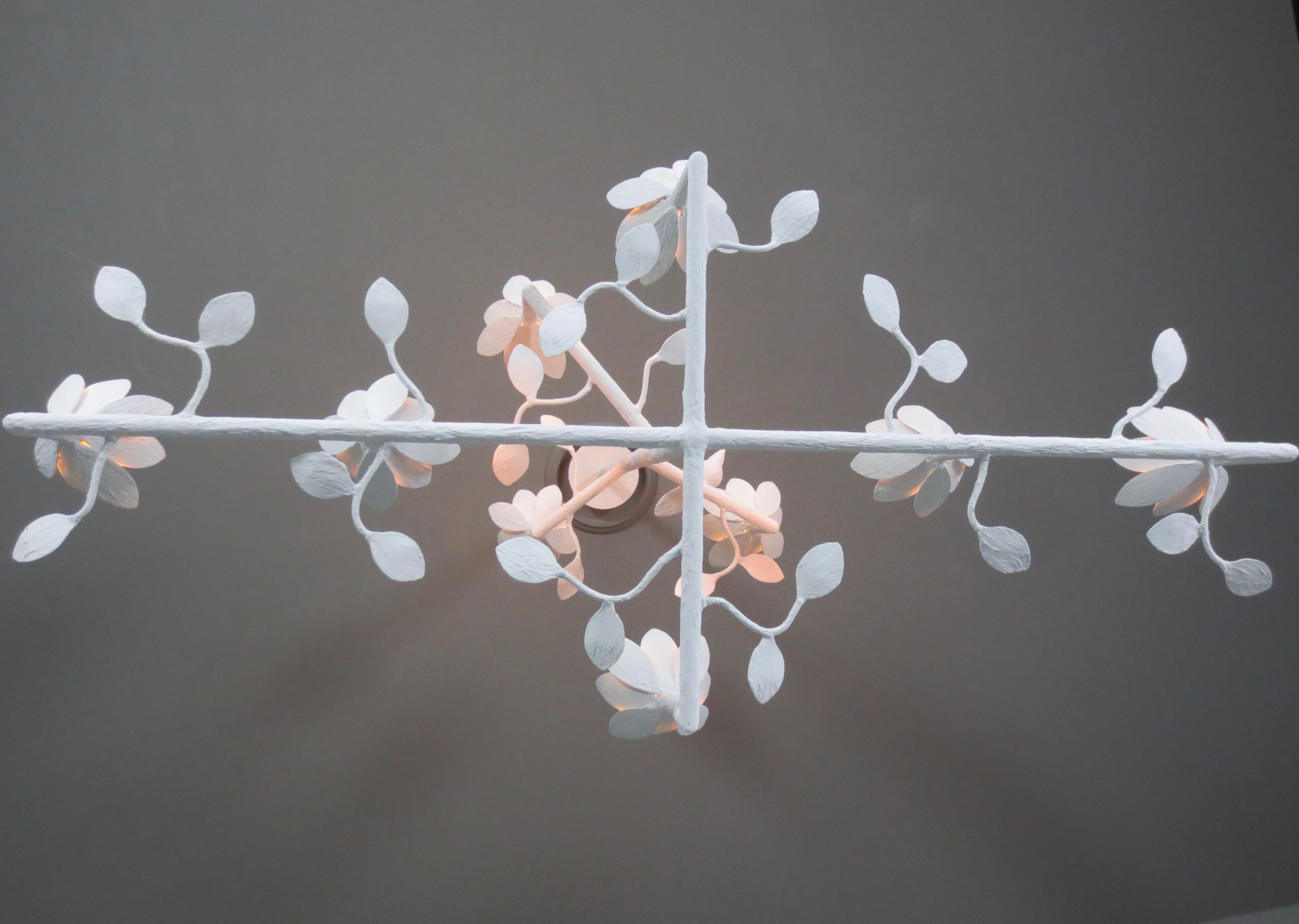 9 bloom cross bar plaster chandelier with birds and leaves by Tracey Garet of Apsara Interiors.
This chandelier has 9 blooms of various heights and is shown in white plaster. A single bird adorns one of the cross bars and leaves are detailed