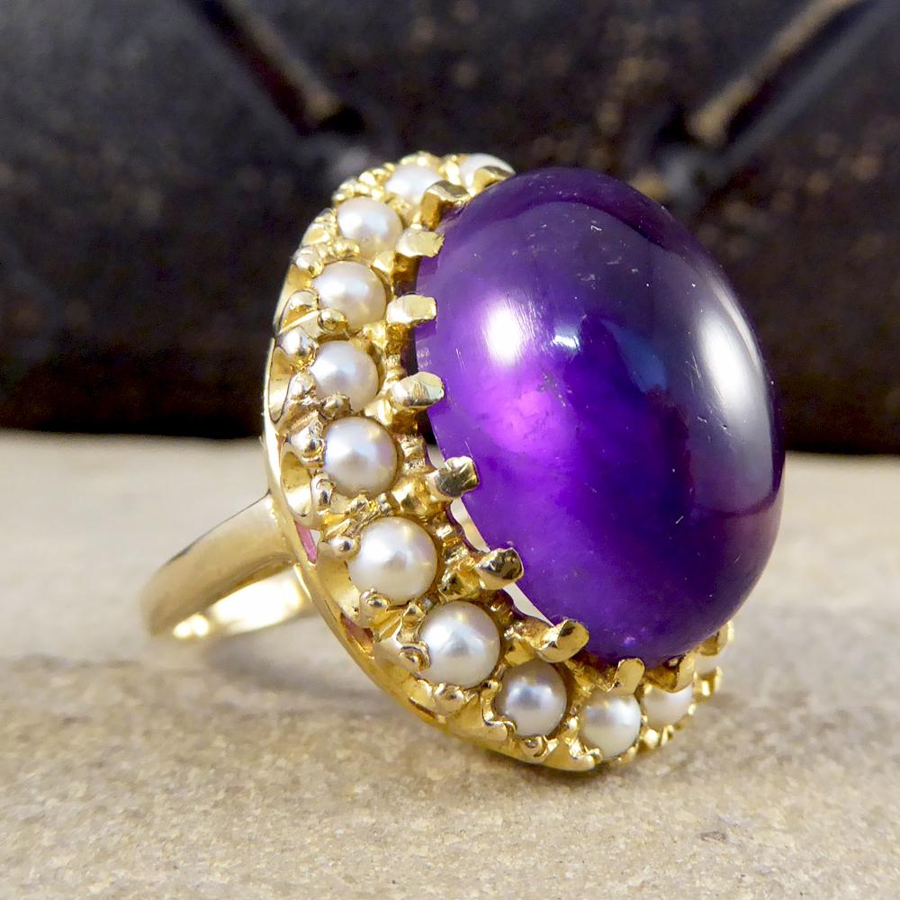For all those who love a larger than life statement piece, this gorgeous vintage ring is just that. Featuring a big and beautiful Cabochon Amethyst enclosed with a cluster of 18 pearls all the way around in a claw setting crafted from 9ct Yellow