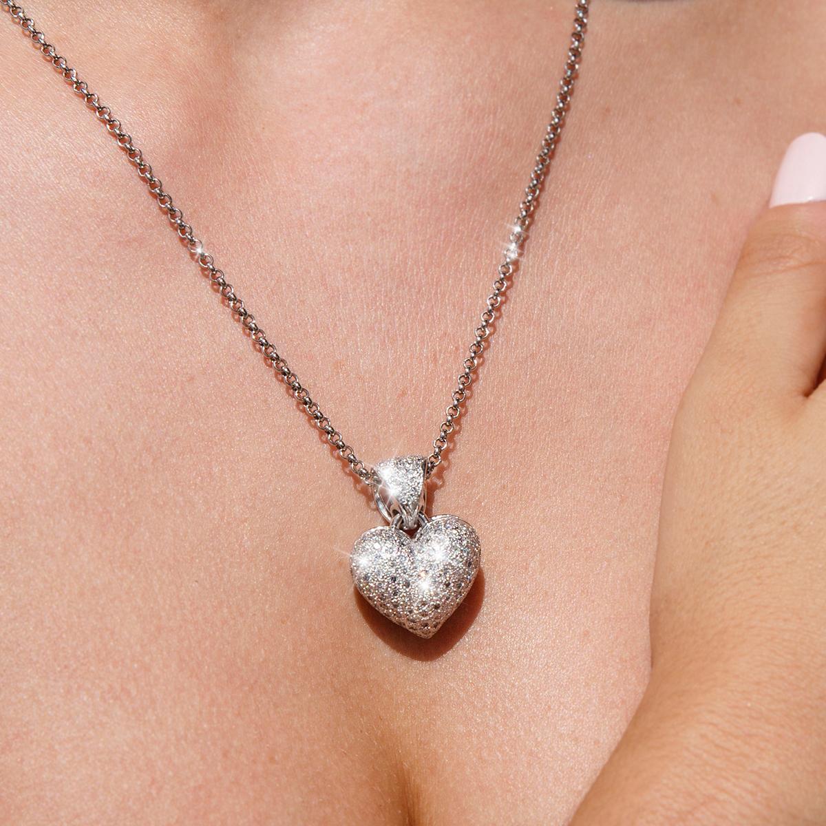 Crafted in 9 carat white gold, this adorable vintage pendant is in the shape of a heart. The front surface of the pendant is encrusted with sparkling pave set round brilliant cut diamonds, and the high polish back features a filigree frame with a
