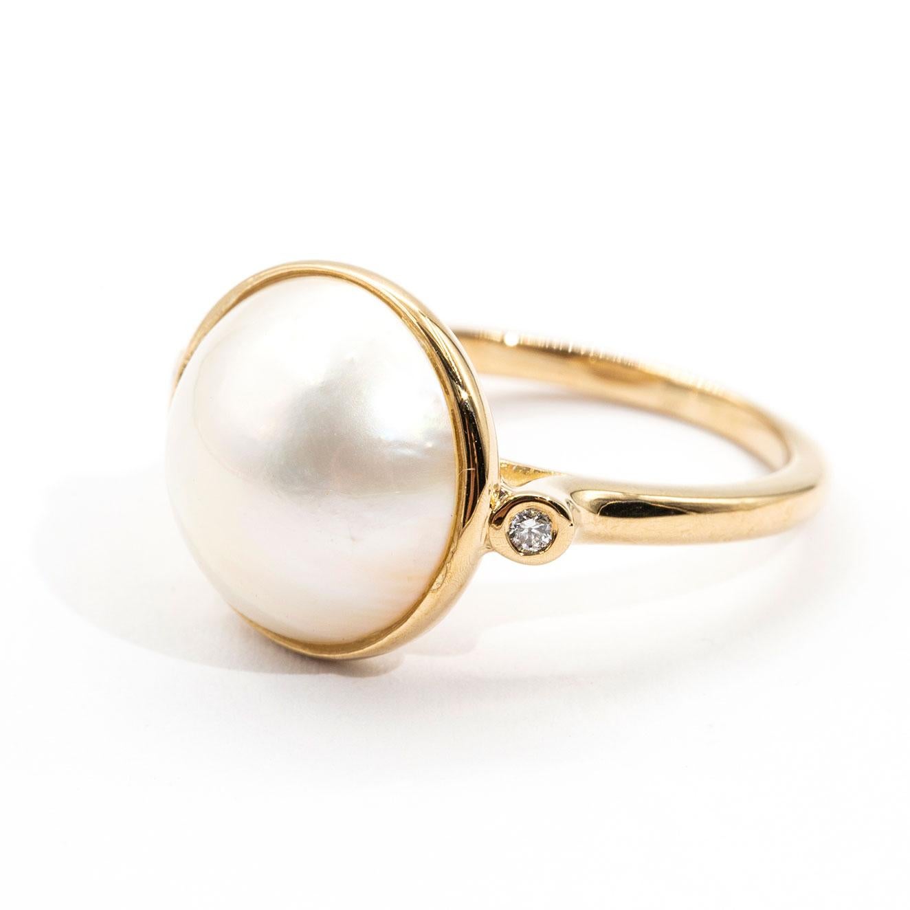 Forged in 9 carat yellow gold is this lovely vintage ring that features a central white mabe pearl flanked by two round diamonds. We have named this darling ring The Dianna Ring. The Dianna Ring is a heart warming traditional design that transitions
