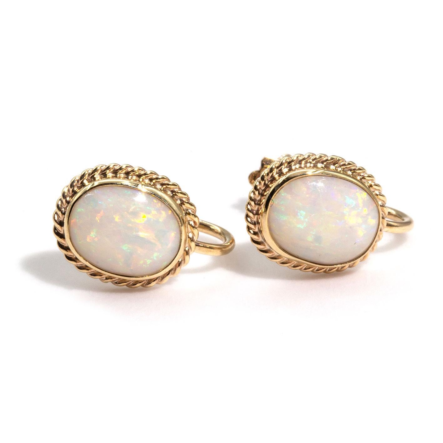 Carefully crafted in 9 carat yellow gold, are these delightful vintage pair of clip on earrings featuring oval cabochon opals displaying orange, yellow, green and blue play of colour. The opals  measure approximately 9x7 millimetres and are