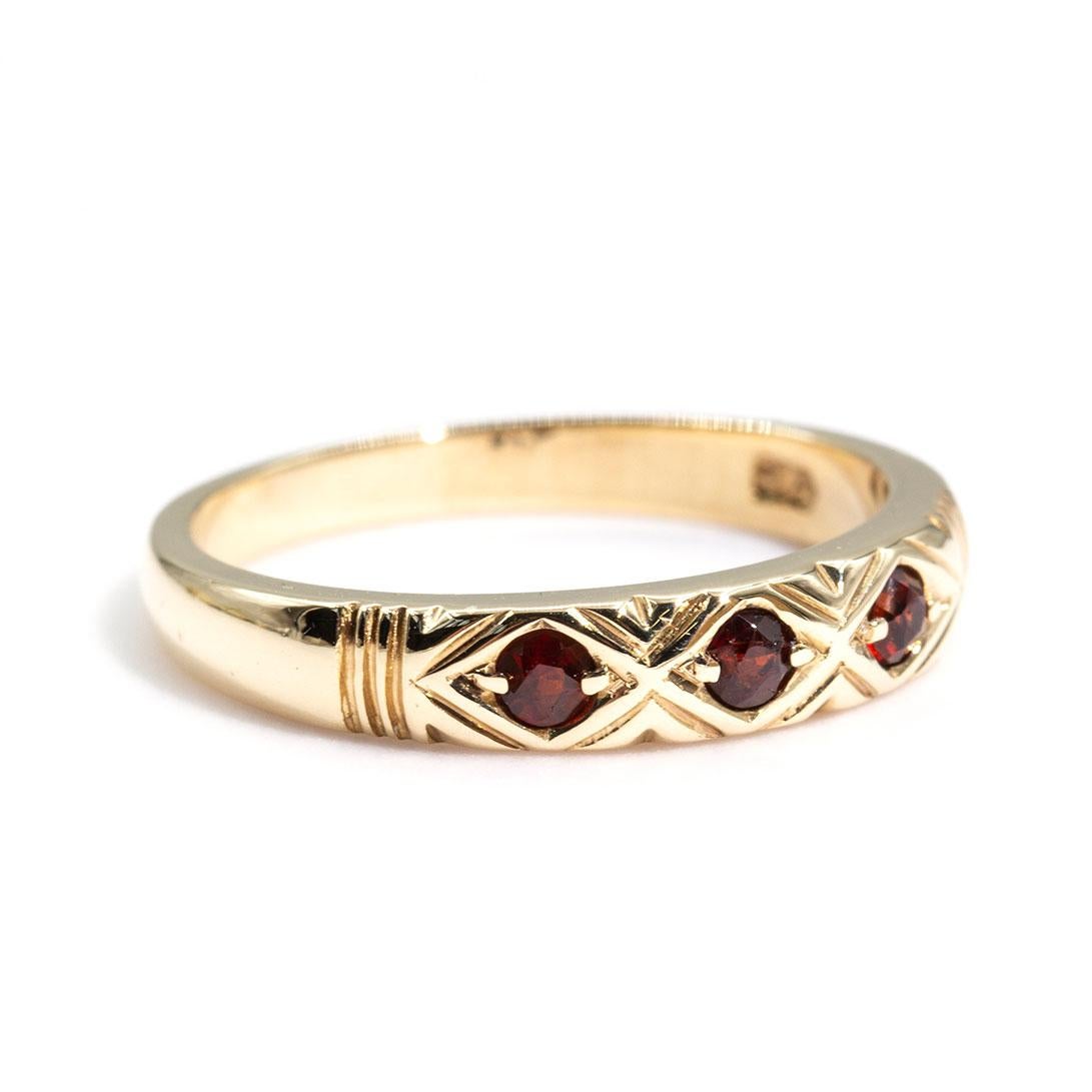 Crafted in 9 carat yellow gold is this charming vintage band ring carefully set with round garnets and are each surrounded by chevron pattern detailing. We have named this gorgeous vintage splendour The Nora Ring. The Nora ring looks wondrous on her